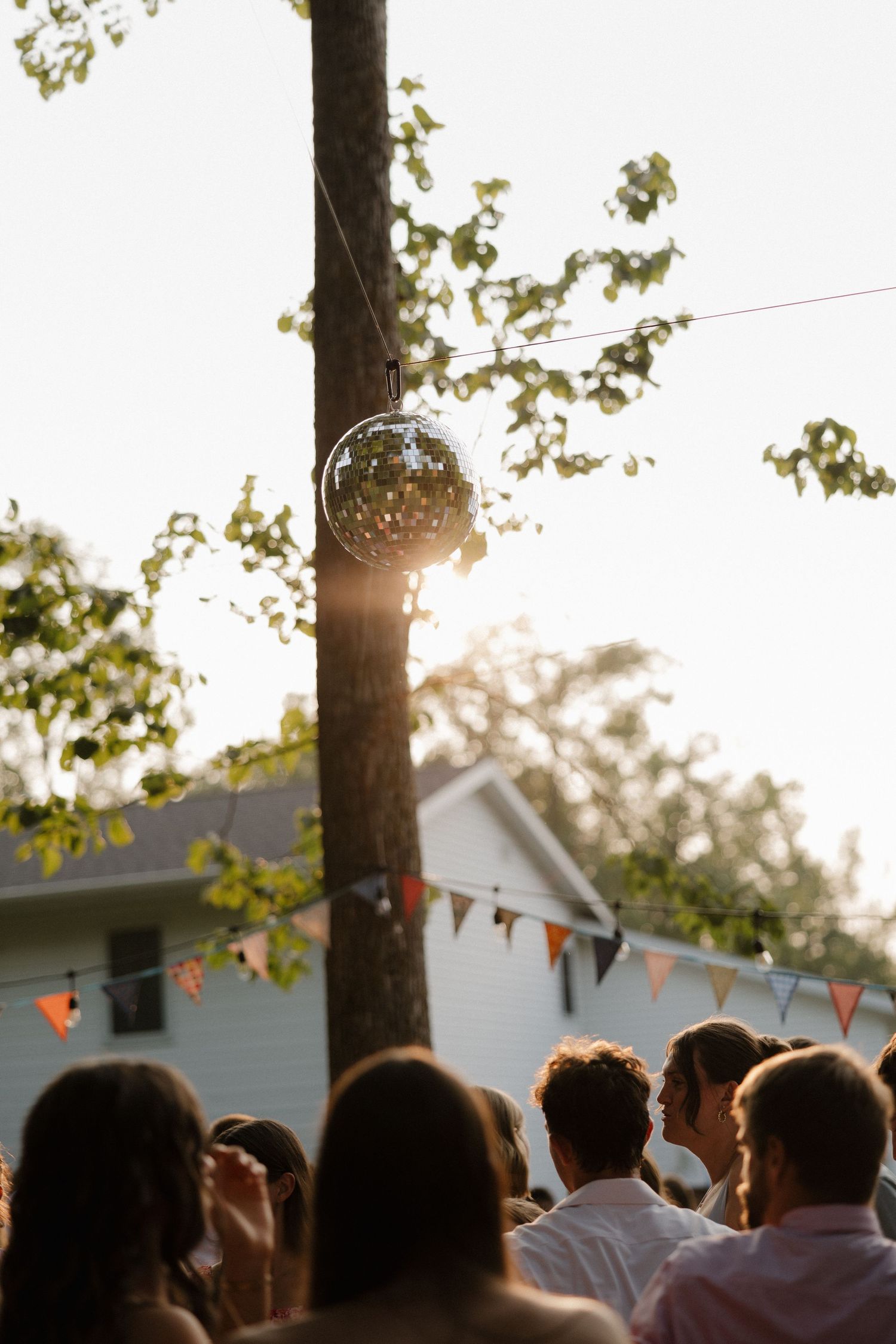 Sunset wedding reception with string lights and bunting decorations.