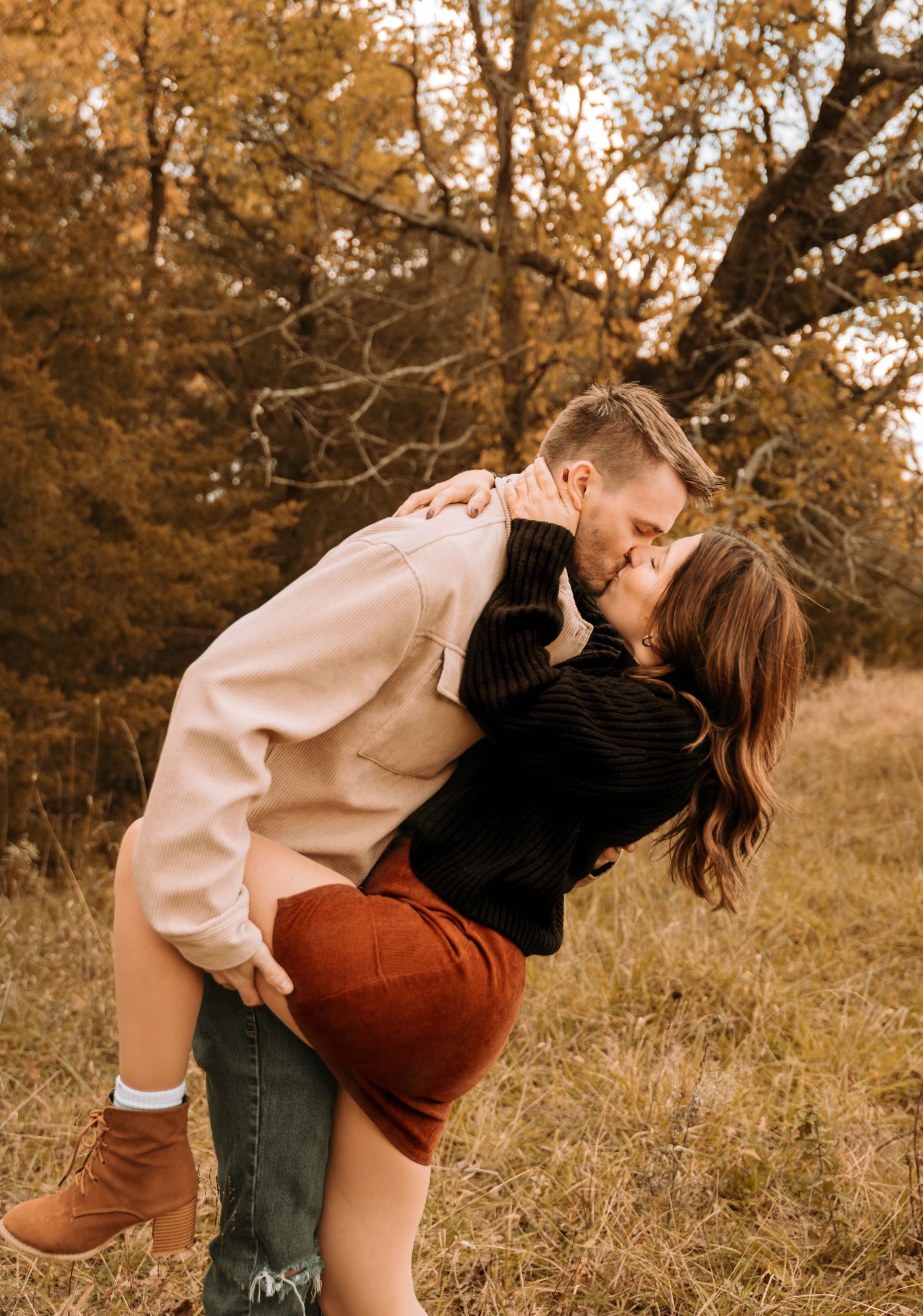 Playful autumn couple photoshoot in a field with warm golden tones.