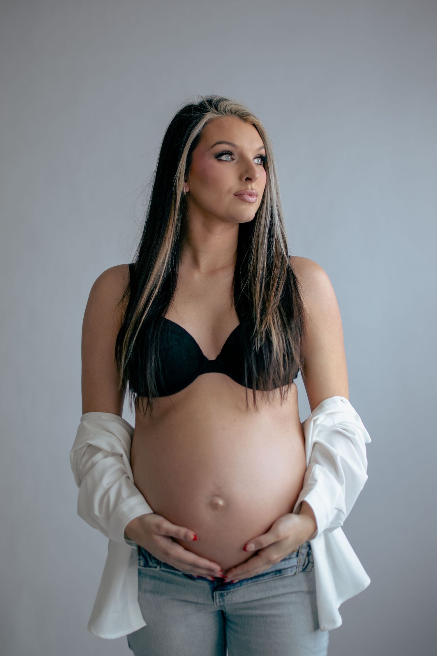 Maternity portrait series showing pregnant belly against grey background.