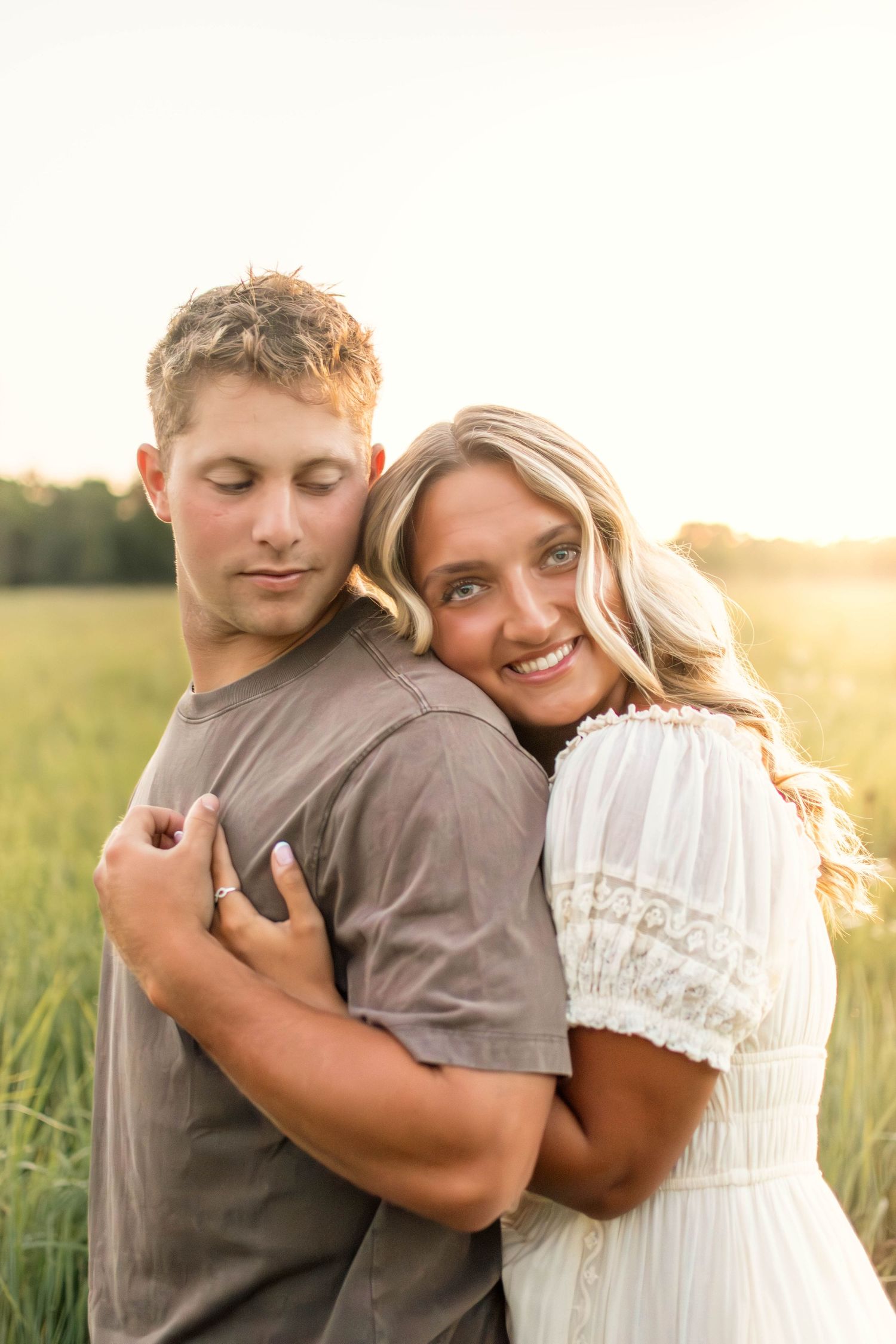 Sweet couple sharing warm hugs in a summer meadow at sunset.