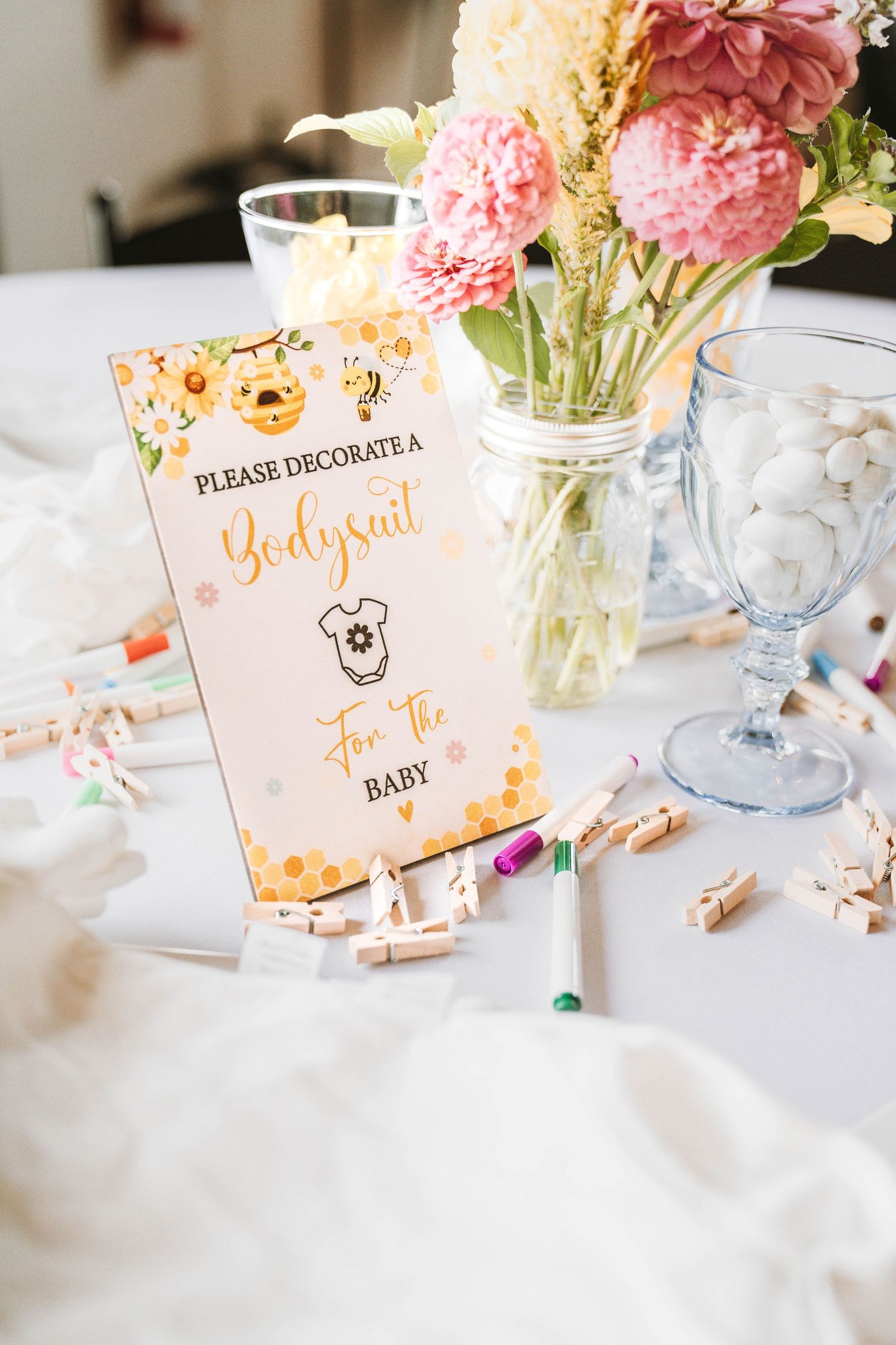 Baby shower table decorations with pink flowers and activity cards.