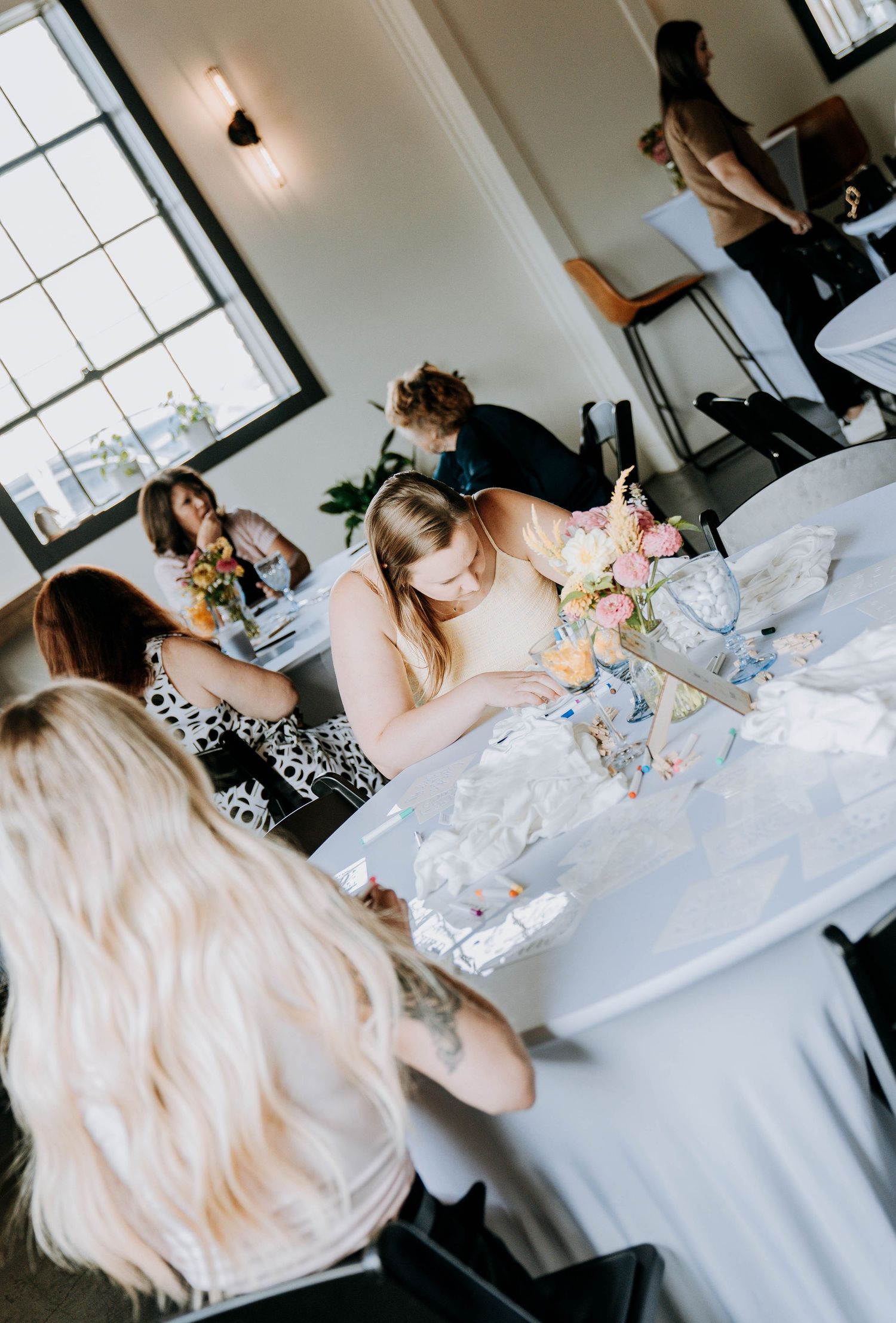Guests gathered around white tables at a baby shower celebration.