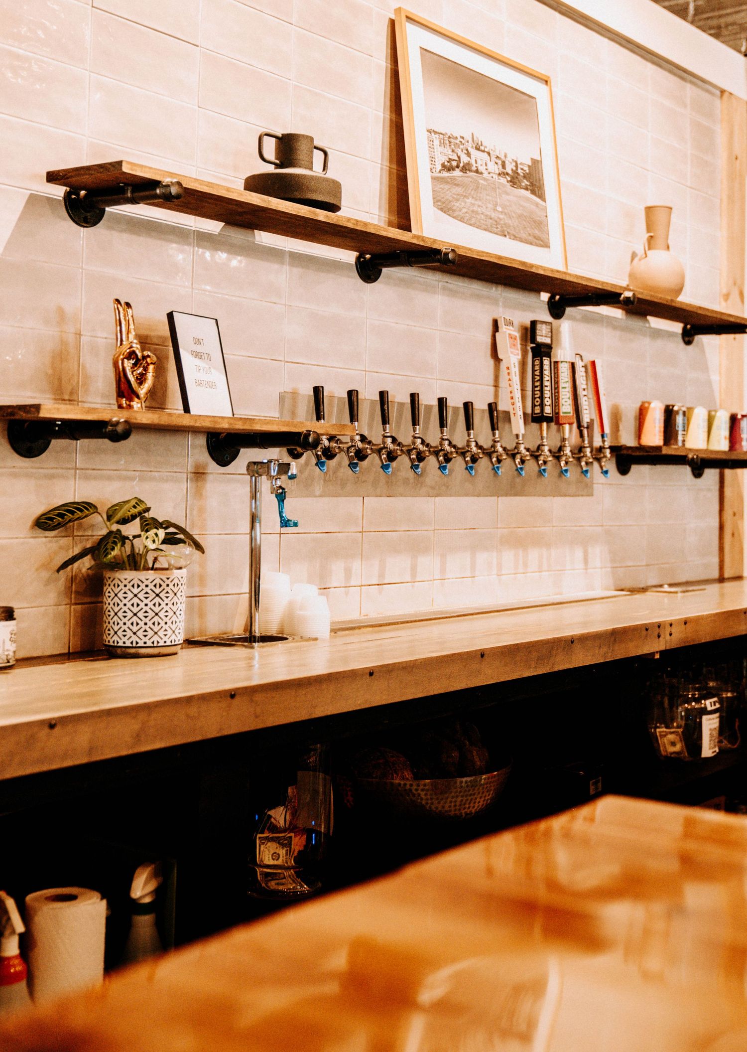 Long wooden bar counter with multiple taps and industrial-style lighting.