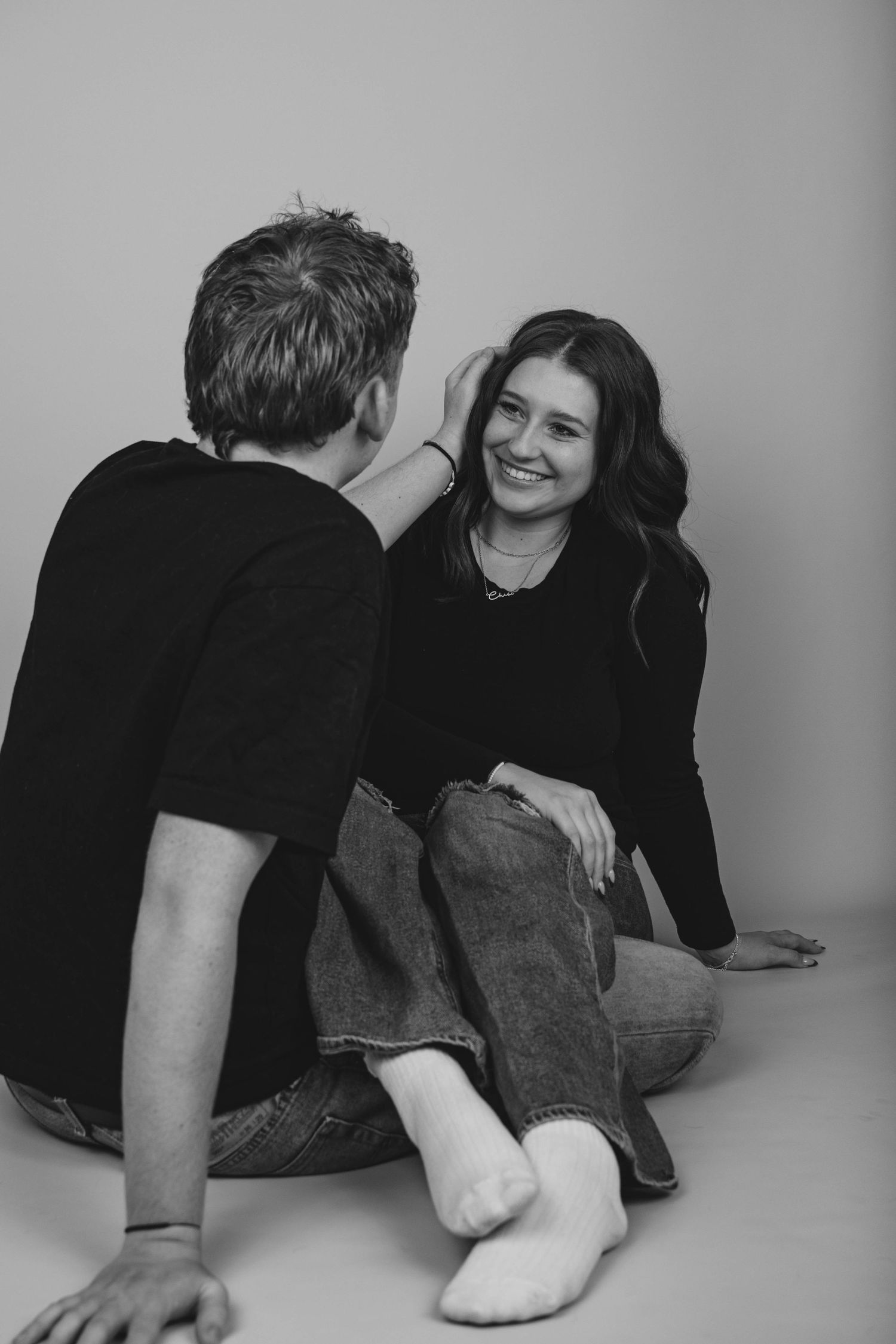 Black and white photo of two people lounging on a studio floor.