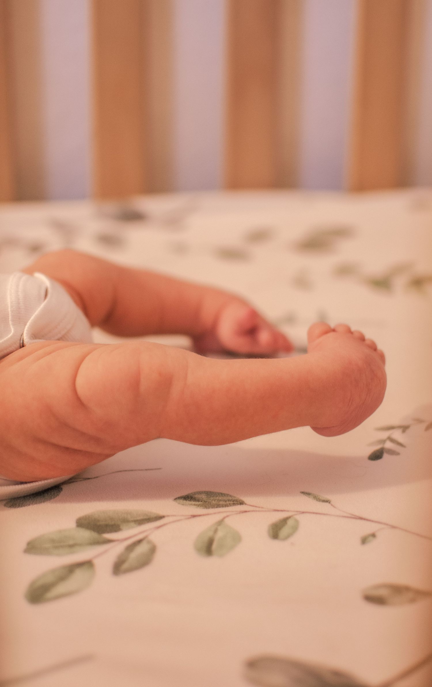 Close-up of tiny baby foot on floral patterned bedding.