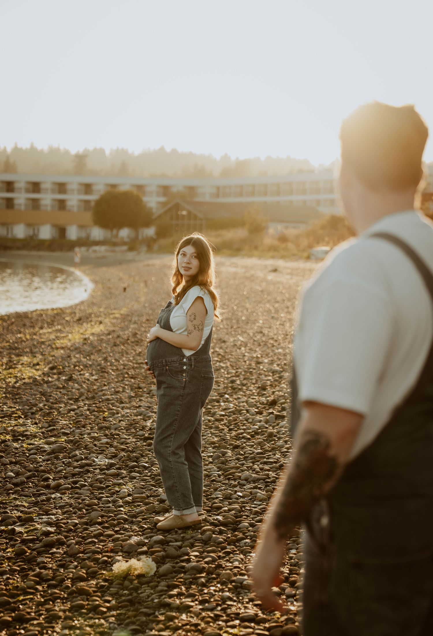 Couple in overalls taking photos at sunset in a field.