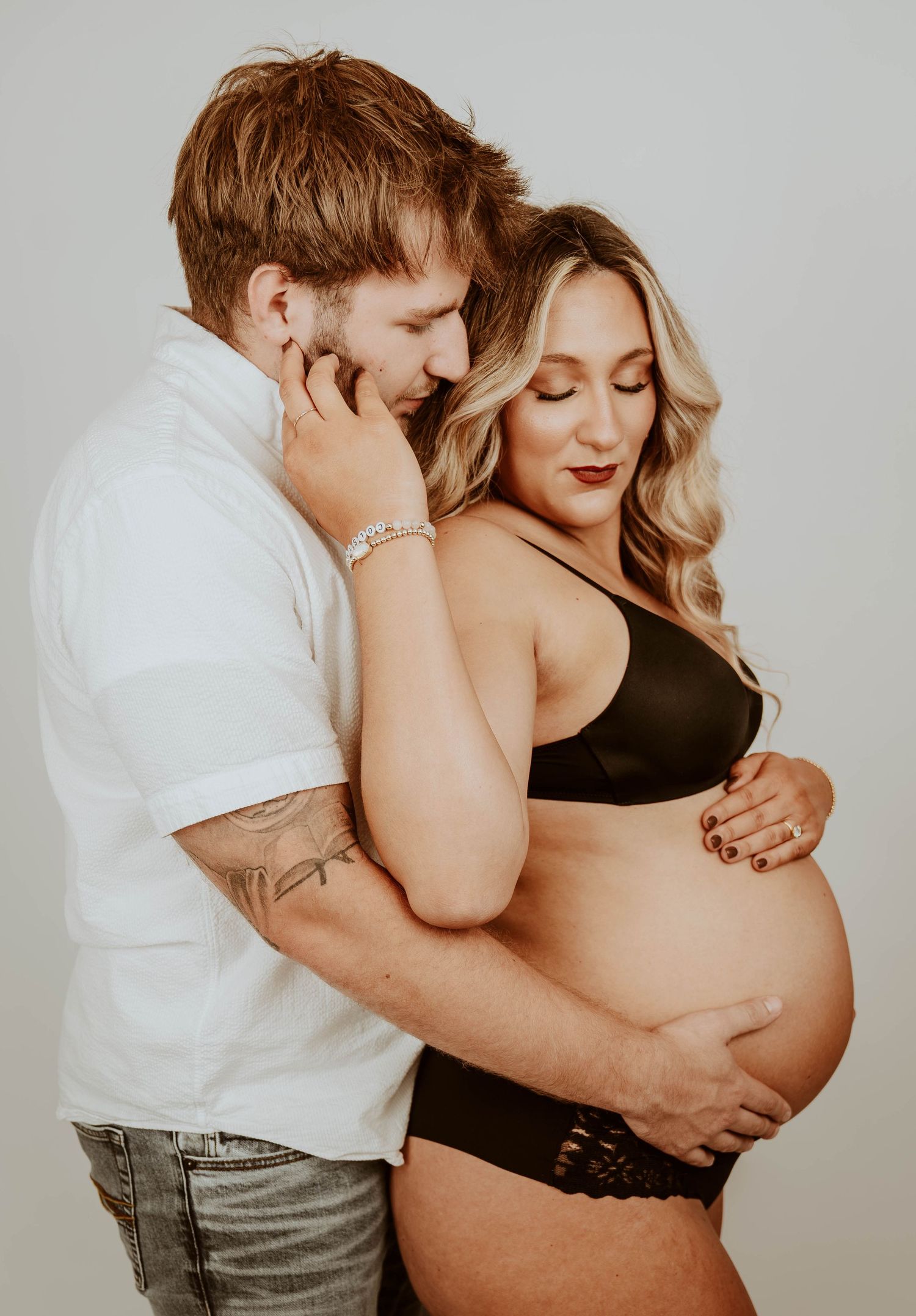 Romantic maternity photoshoot with couple embracing and showing affection for pregnant belly.