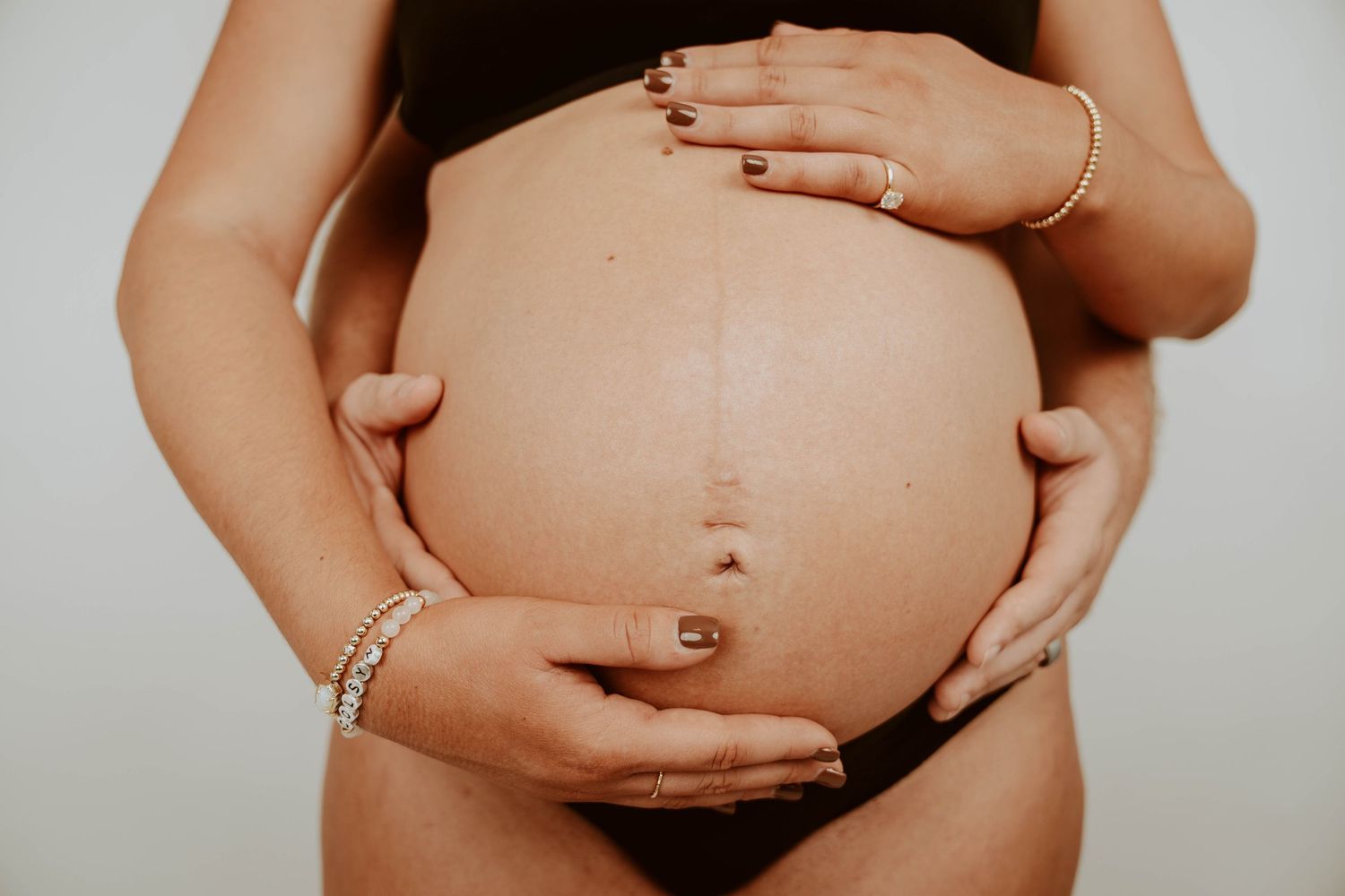 A series of intimate maternity photos showing a pregnant belly in various stages against a light background.