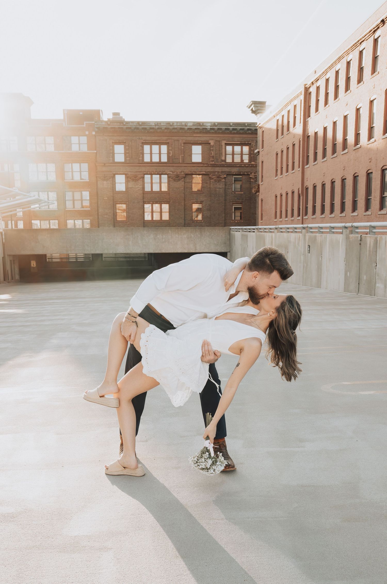 A dance sequence showing graceful movements and dips against an urban backdrop with brick buildings and sunlight.