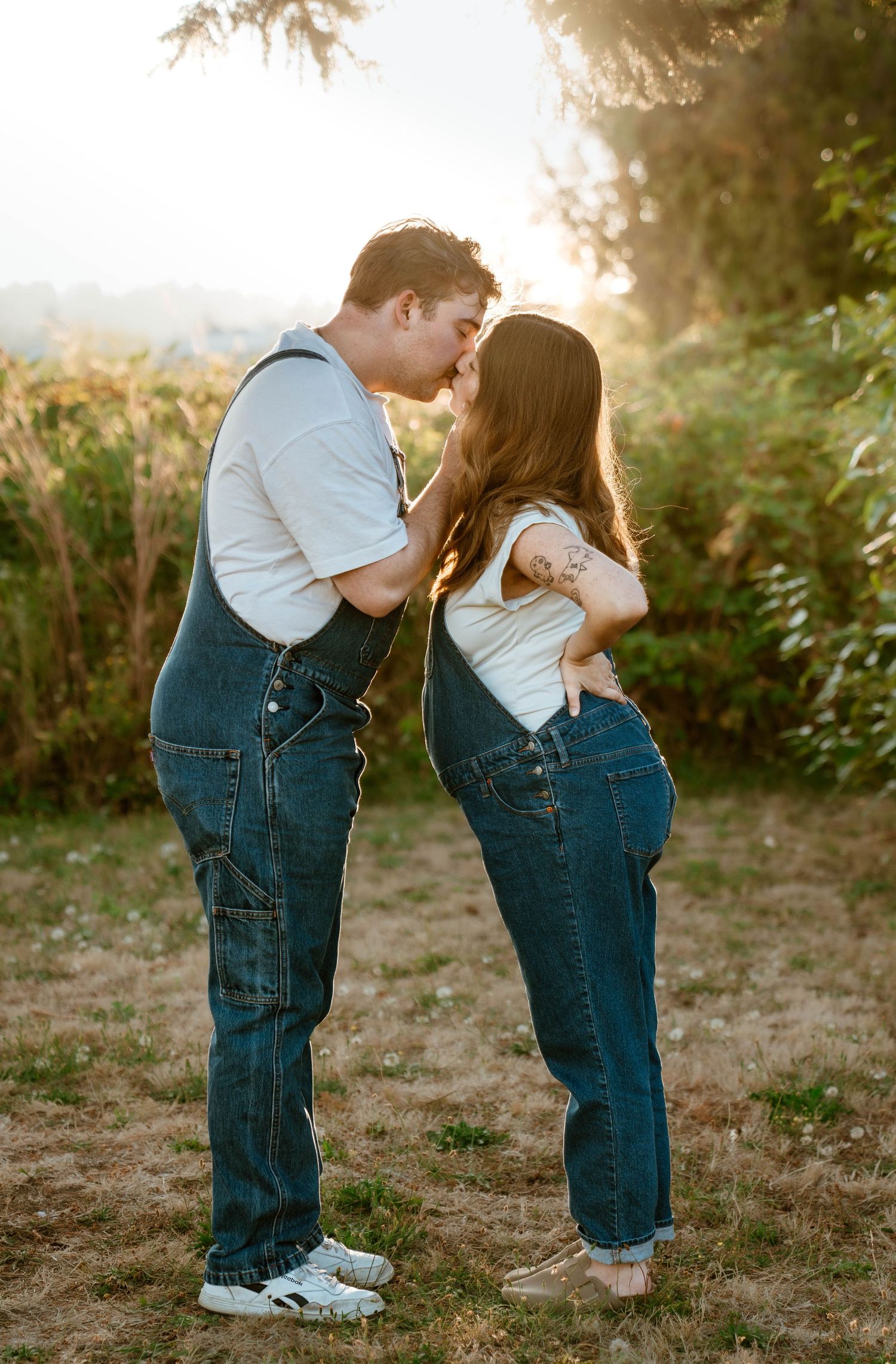 Sweet couple in matching denim overalls sharing intimate moment outdoors.