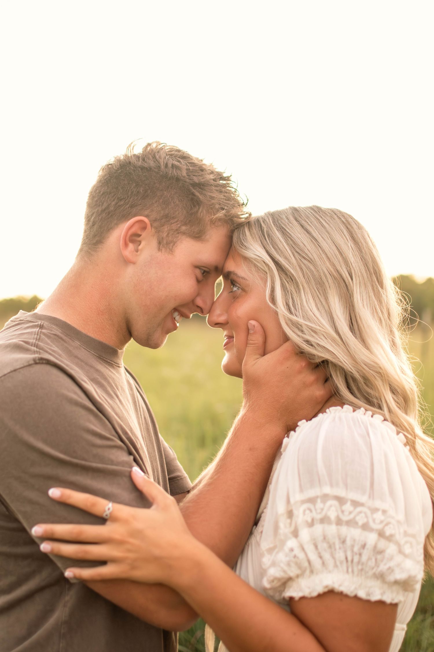 Intimate moment between couple sharing tender embrace in sunlit field.