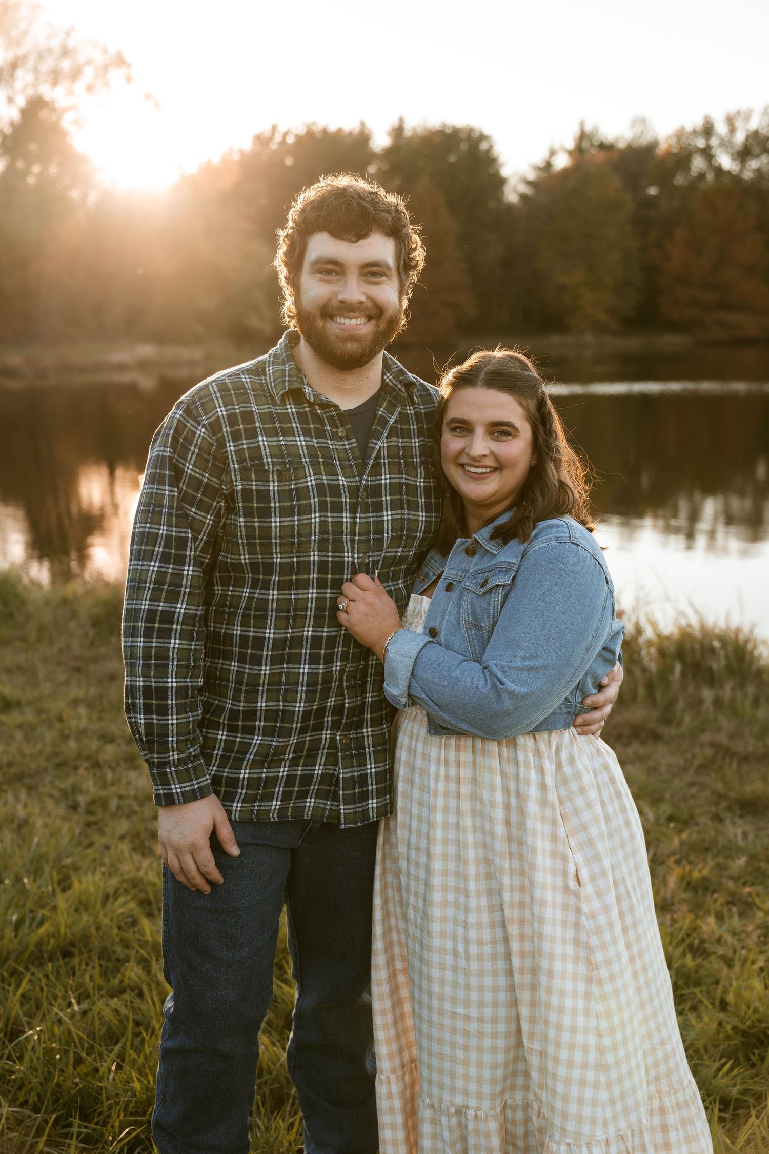Couple posing by a lake during golden hour sunset.