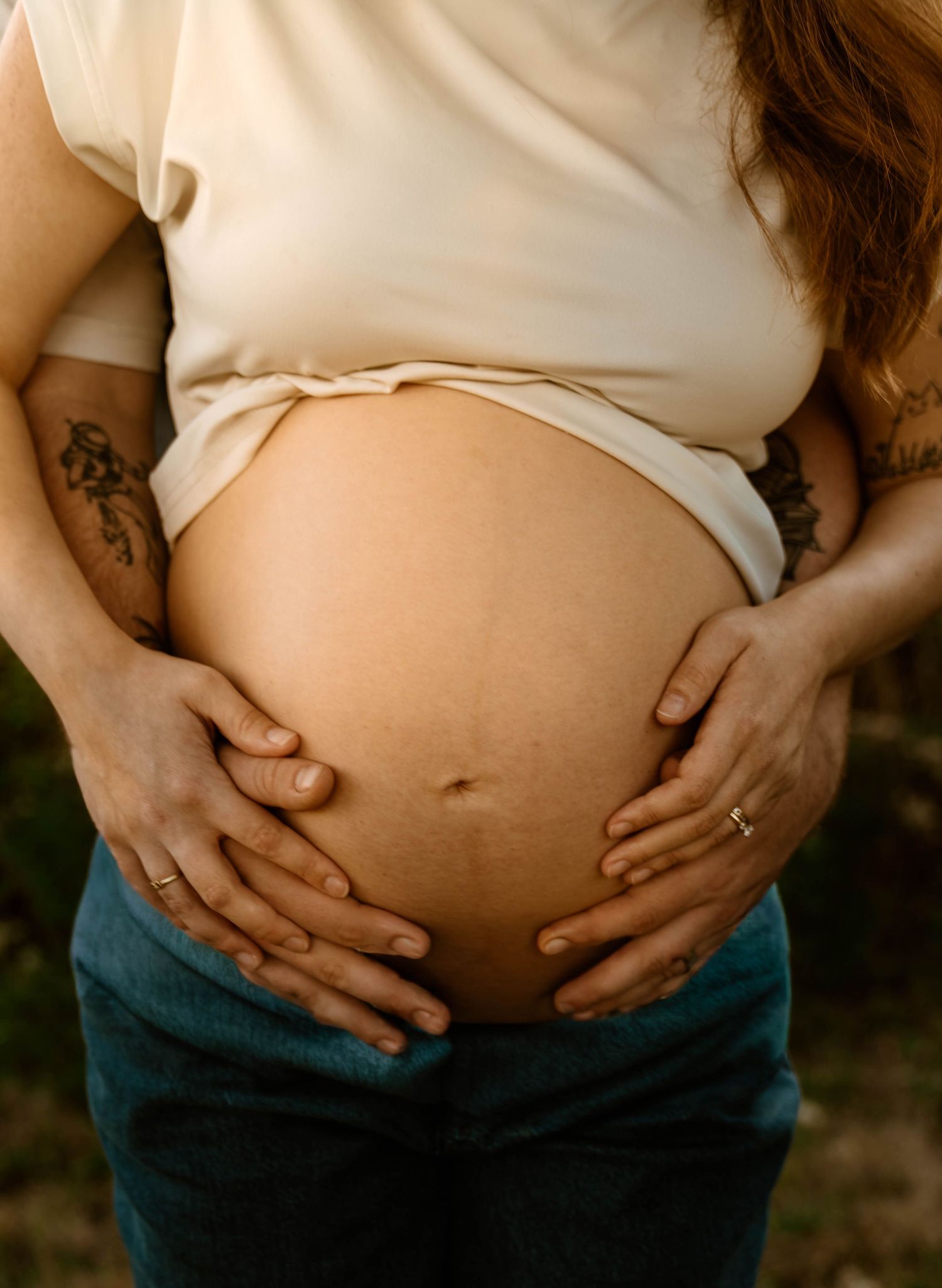 Close-up series of hands cradling pregnant belly while wearing denim overalls.