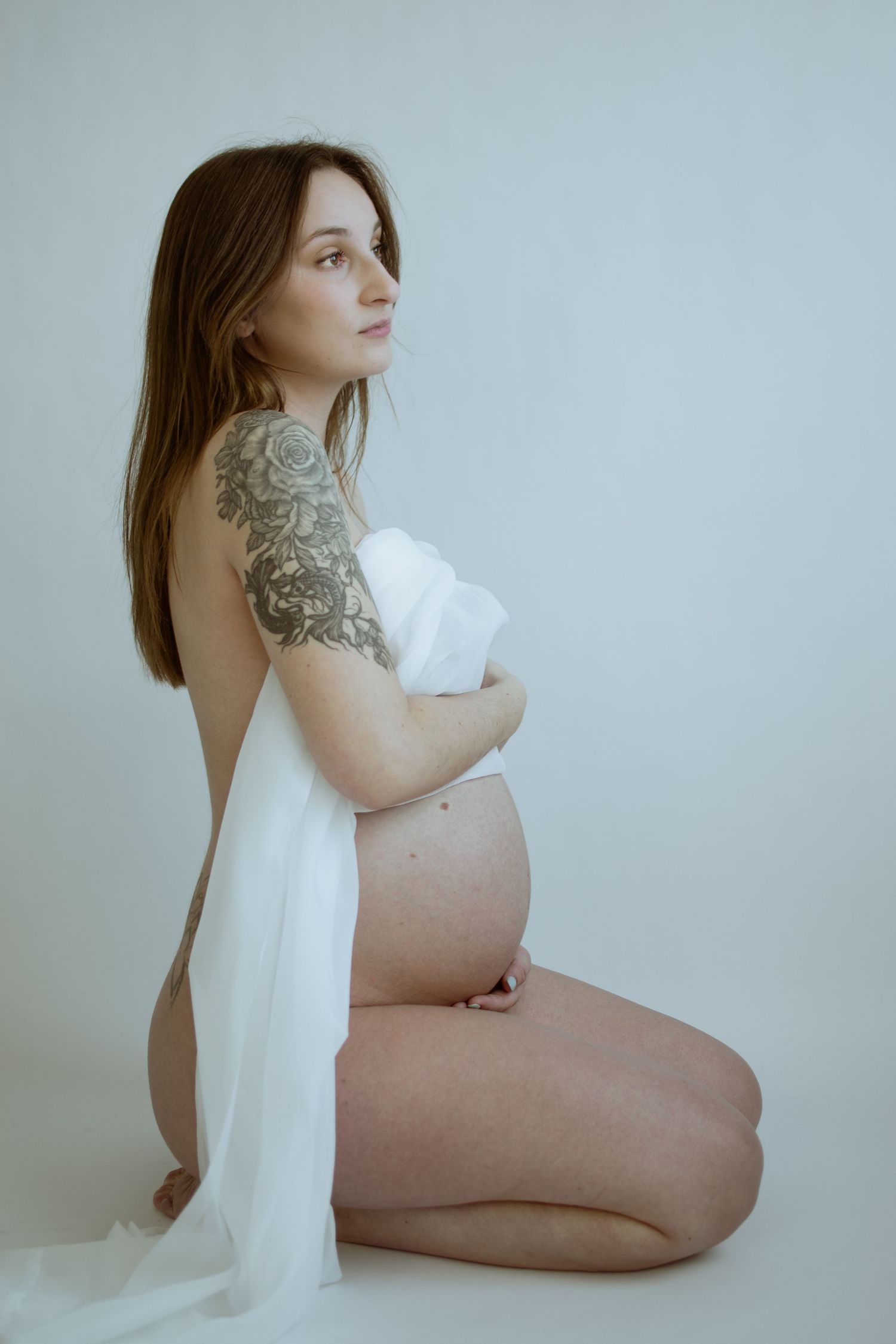 Side view of an expectant mother in minimalist setting wearing white.