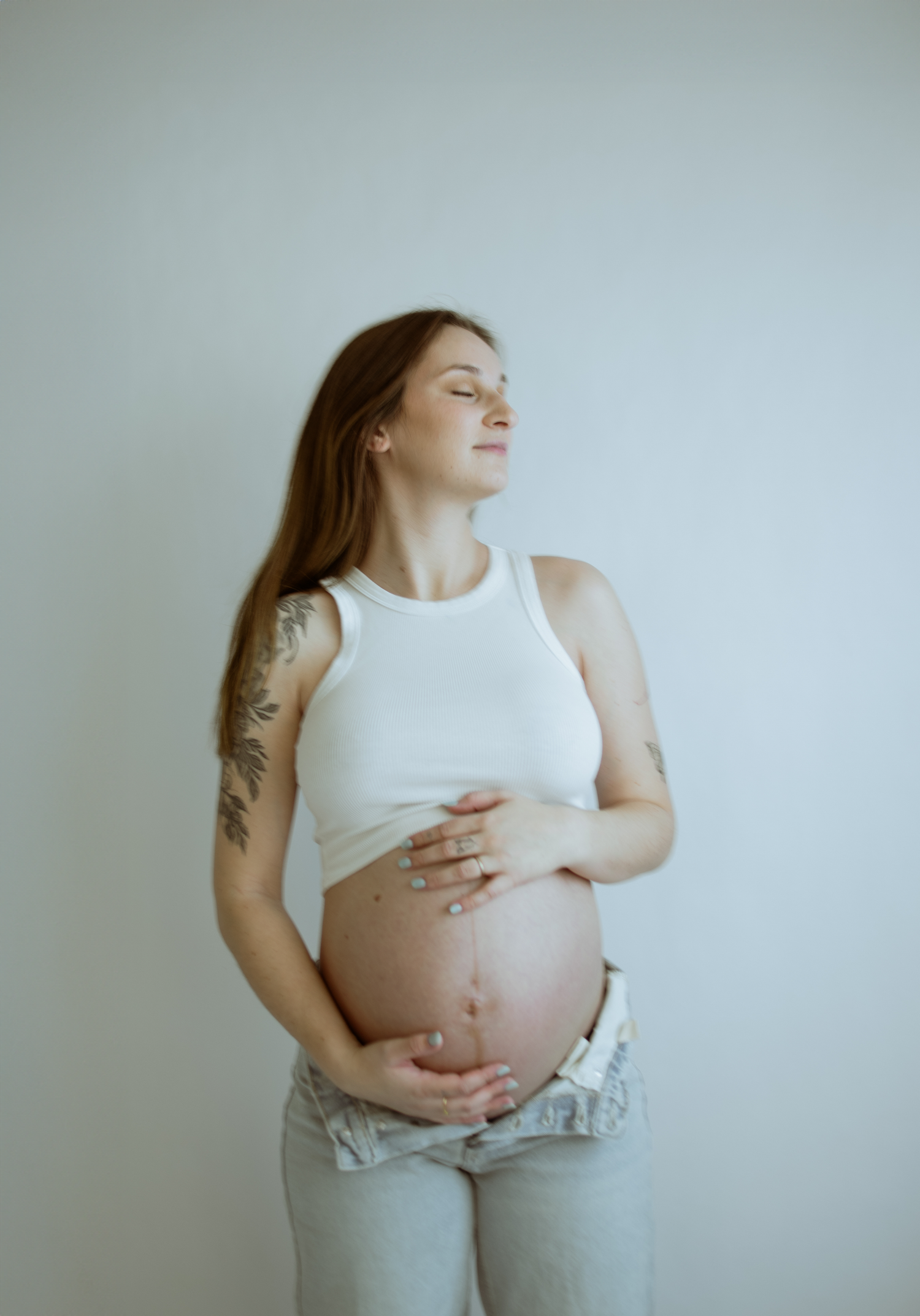 Intimate maternity portraits in white clothing against neutral backdrop.