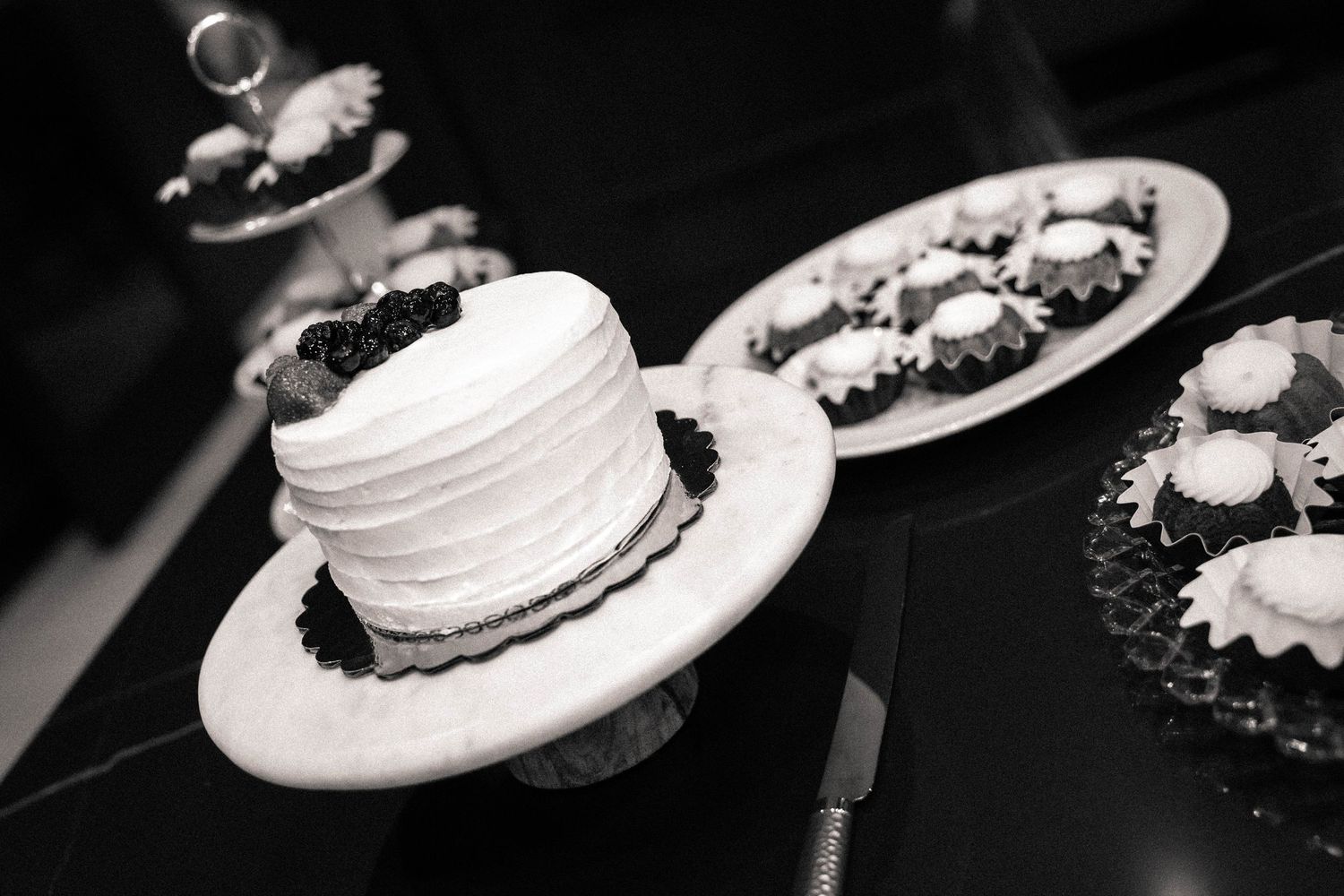 Black and white close-up of elegant plated desserts at formal event.
