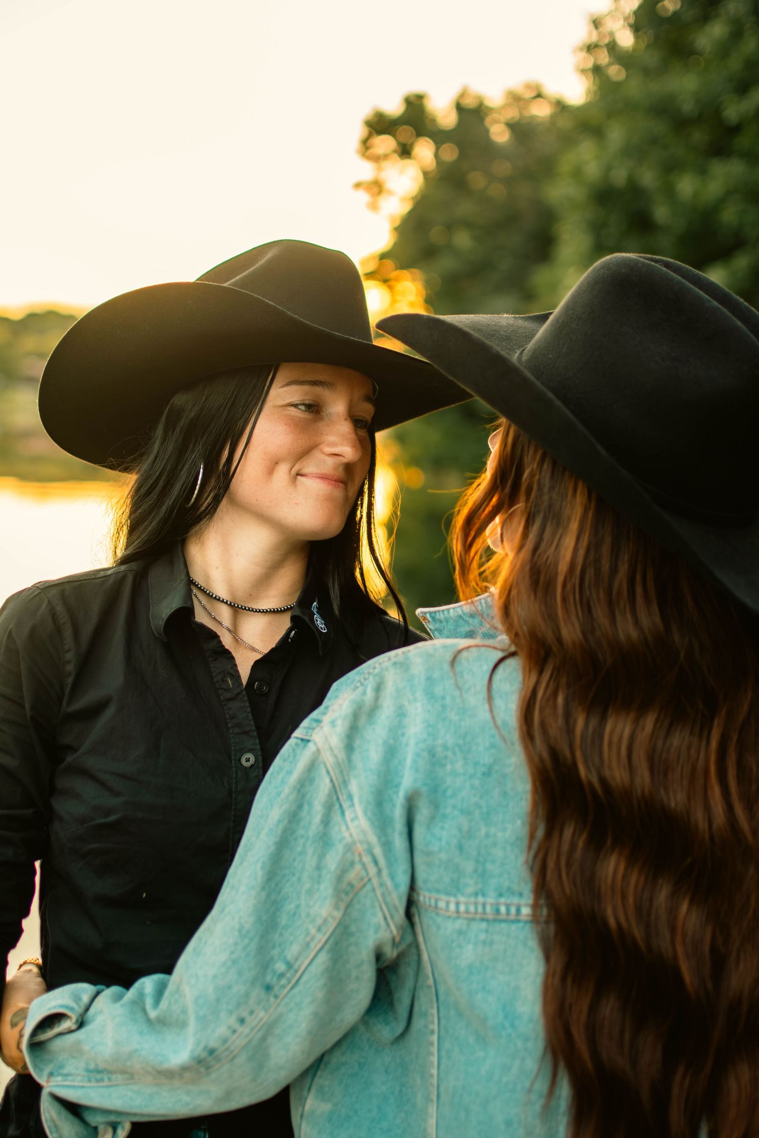 Intimate sunset portrait session featuring black cowboy hats and casual western wear.