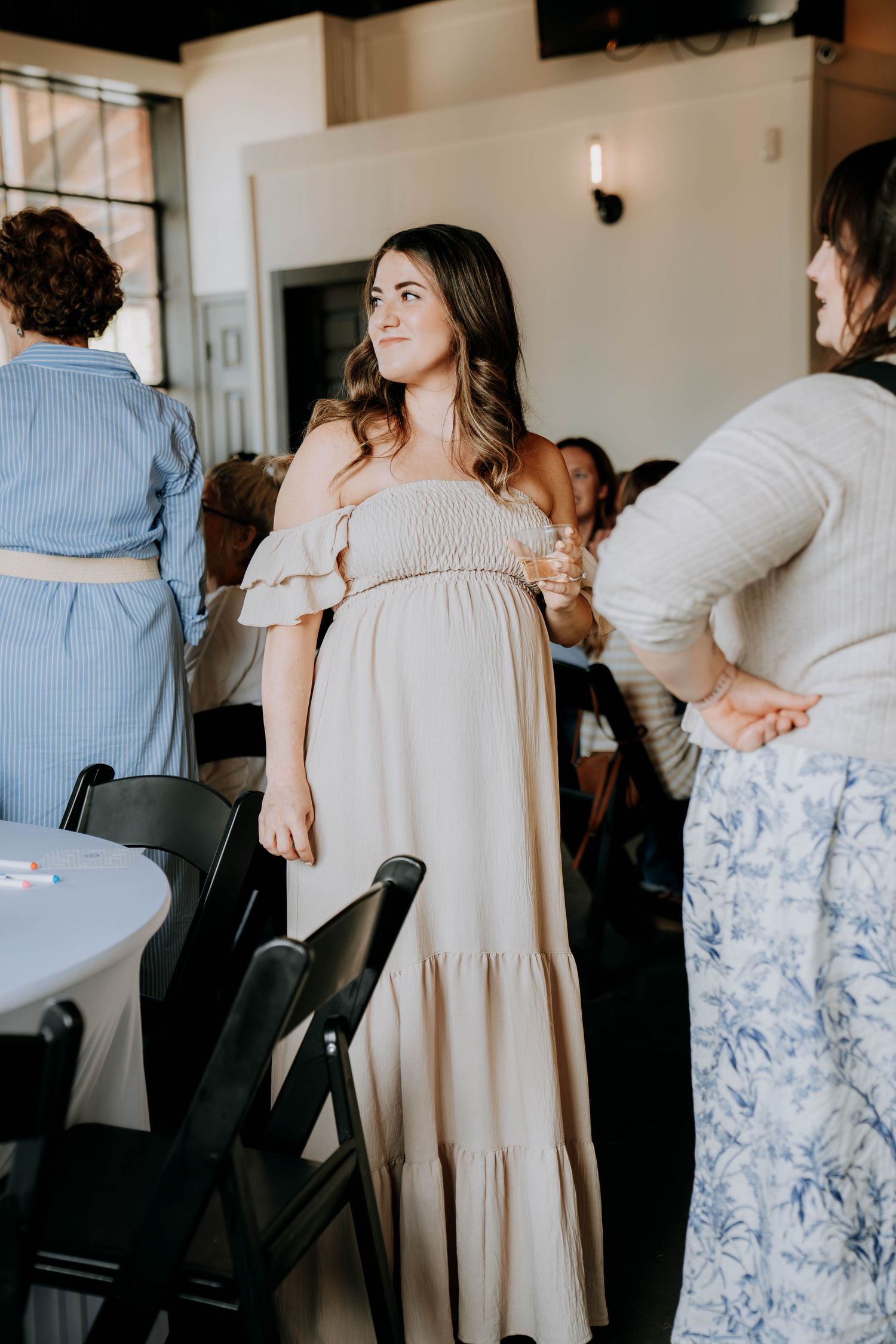 Group gathered in casual setting wearing light colored dresses and floral patterns.
