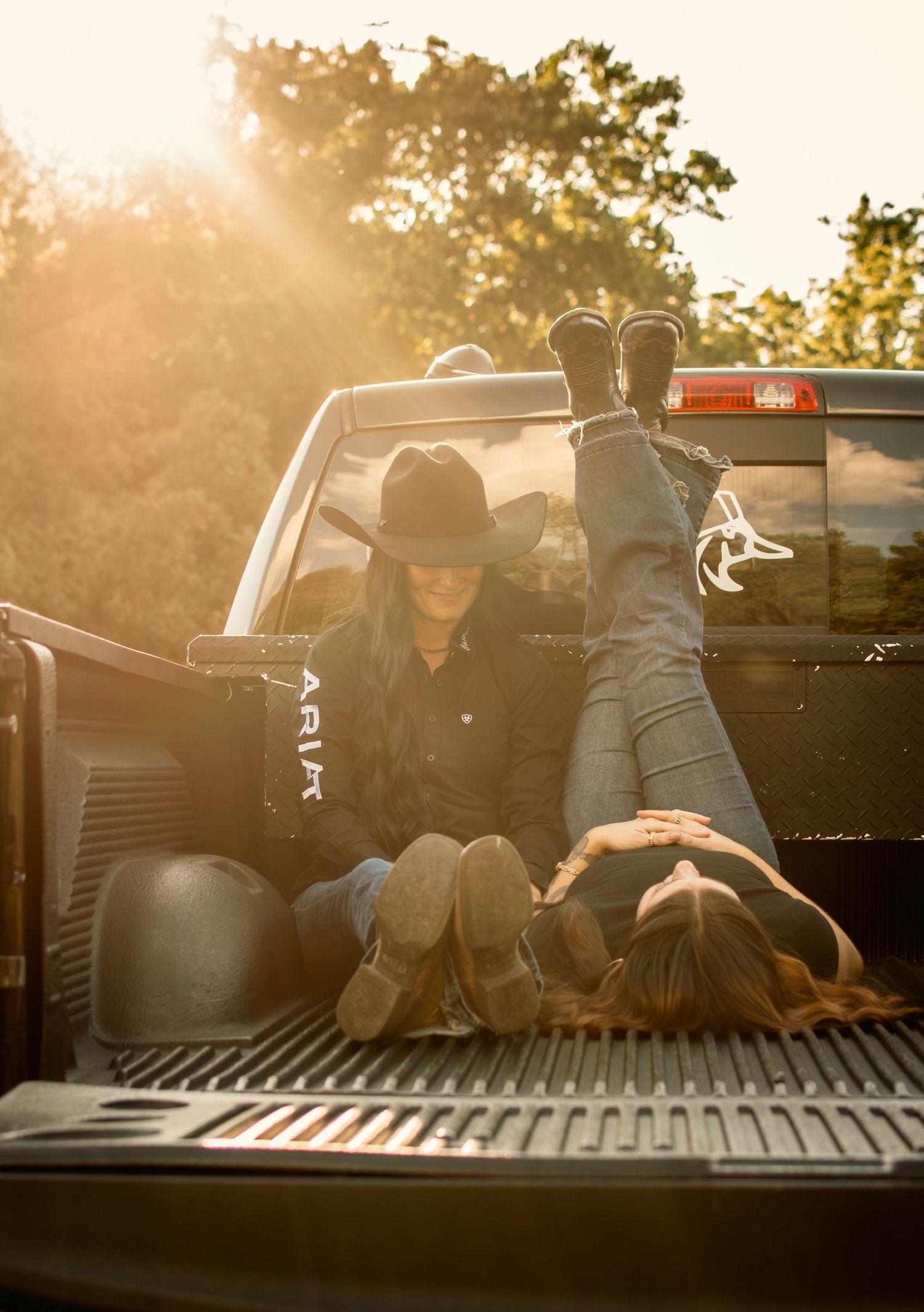 Couple relaxing in pickup truck bed during sunset.