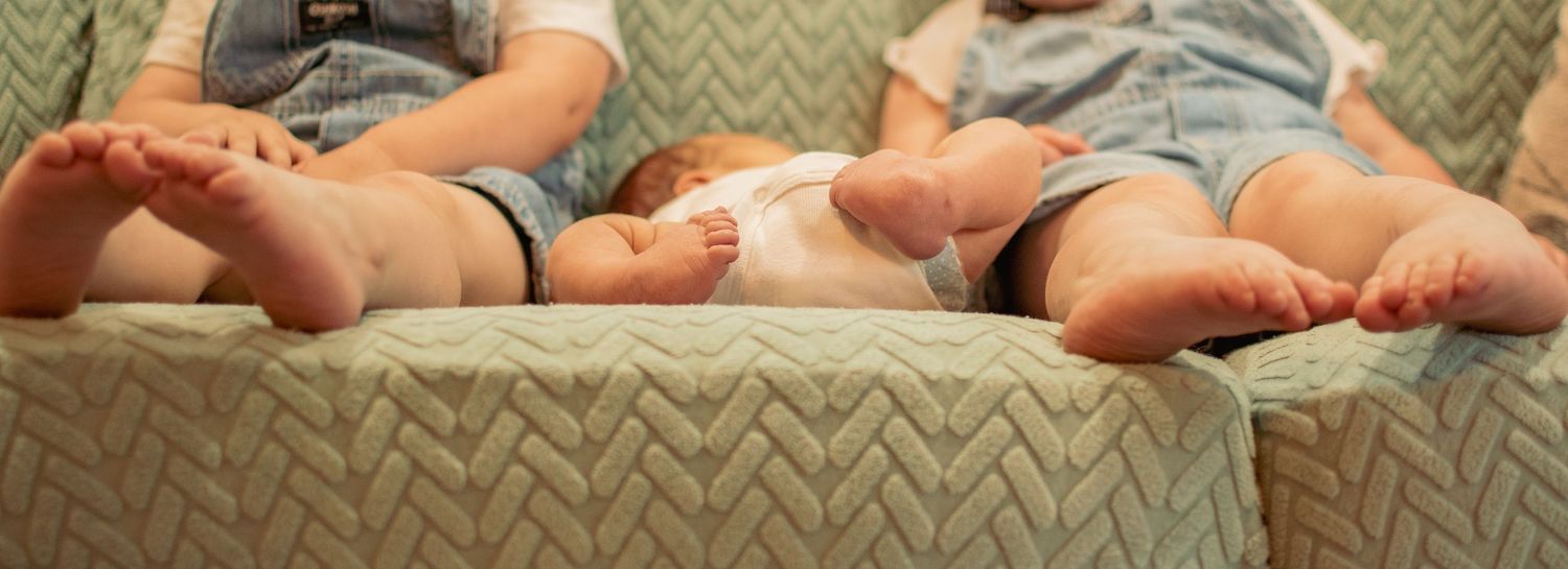 Row of bare feet belonging to family members resting on chevron patterned couch.