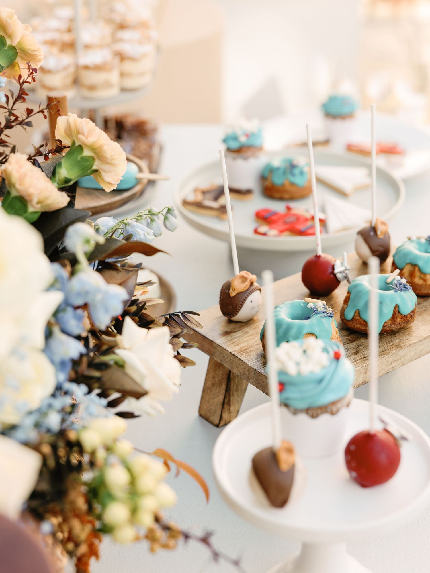 Elegant dessert display featuring chocolate covered cake pops and blue frosted treats on white serving platters.