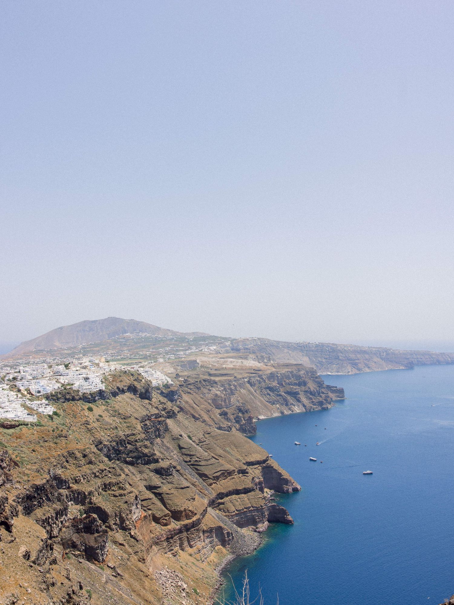 Panoramic view of the Santorini caldera with blue waters and volcanic cliffs.