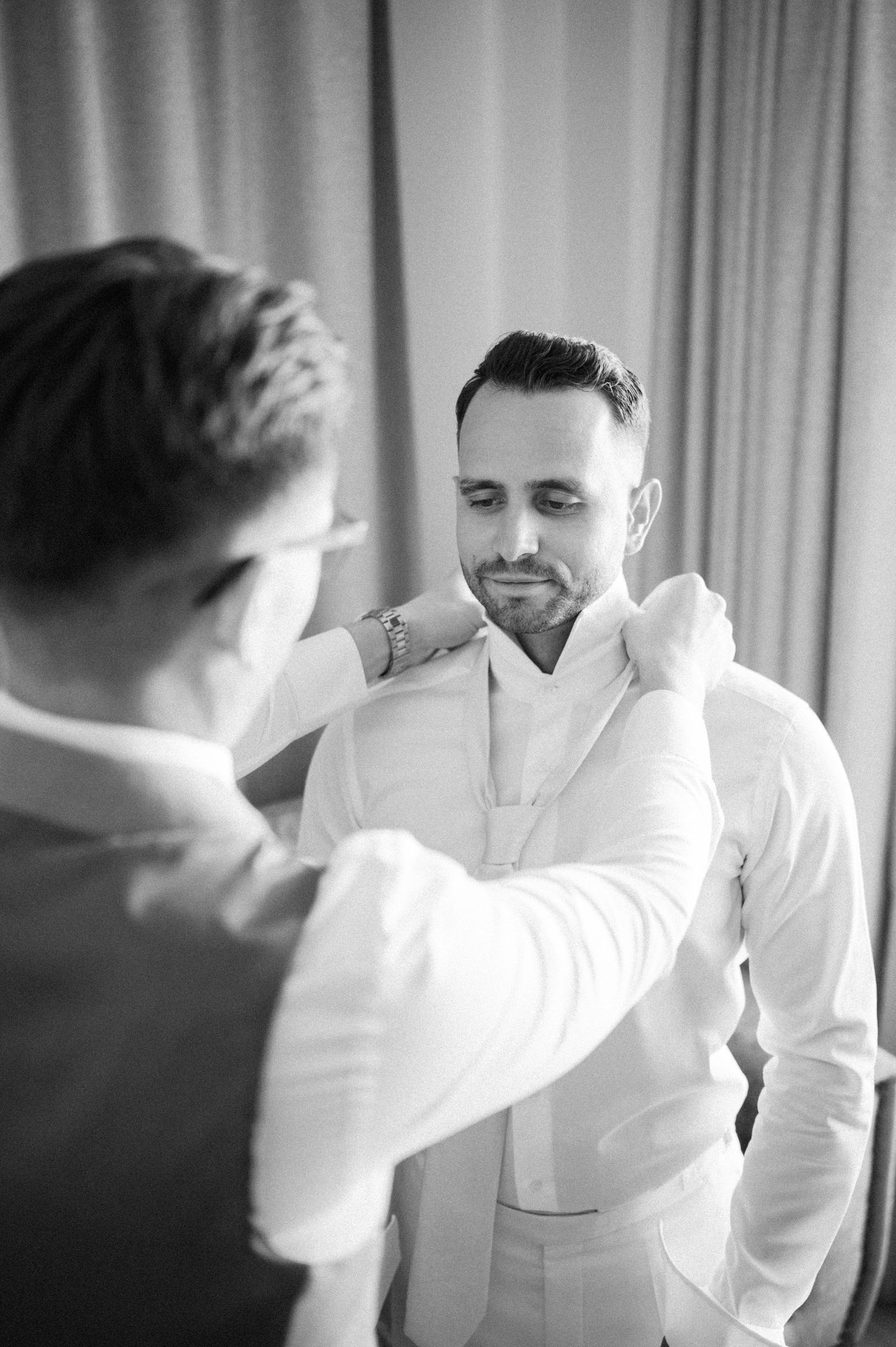 Black and white image of wedding preparation moments in a hotel room.