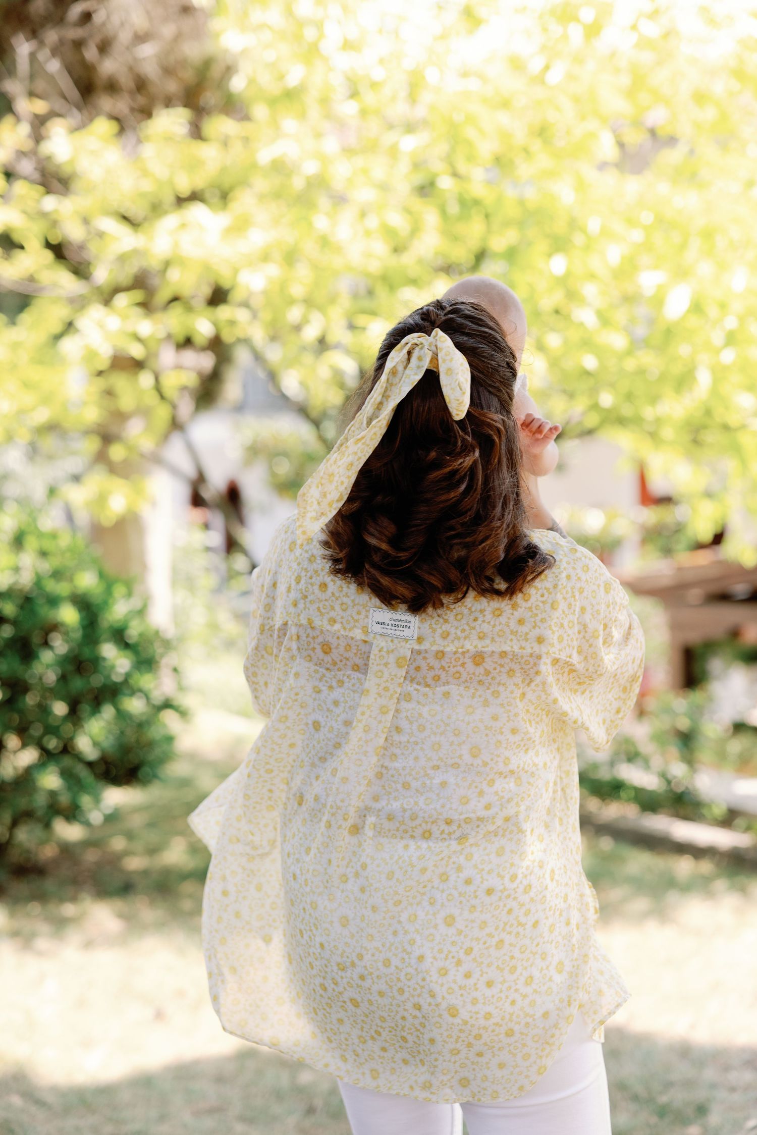 Flowing polka dot dress captured in motion against a sunlit garden backdrop.