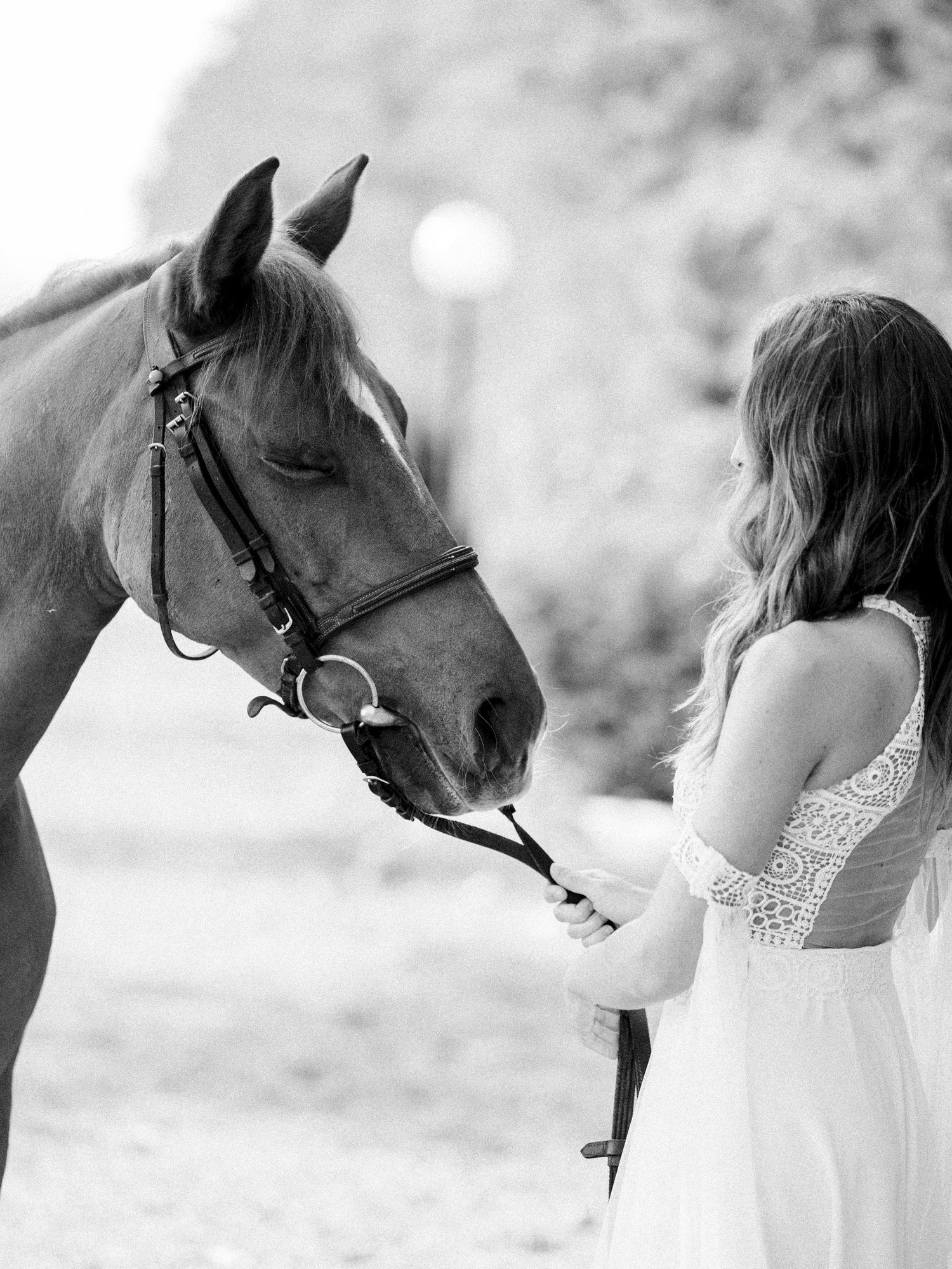 Black and white portrait of bride with horse in intimate moment.