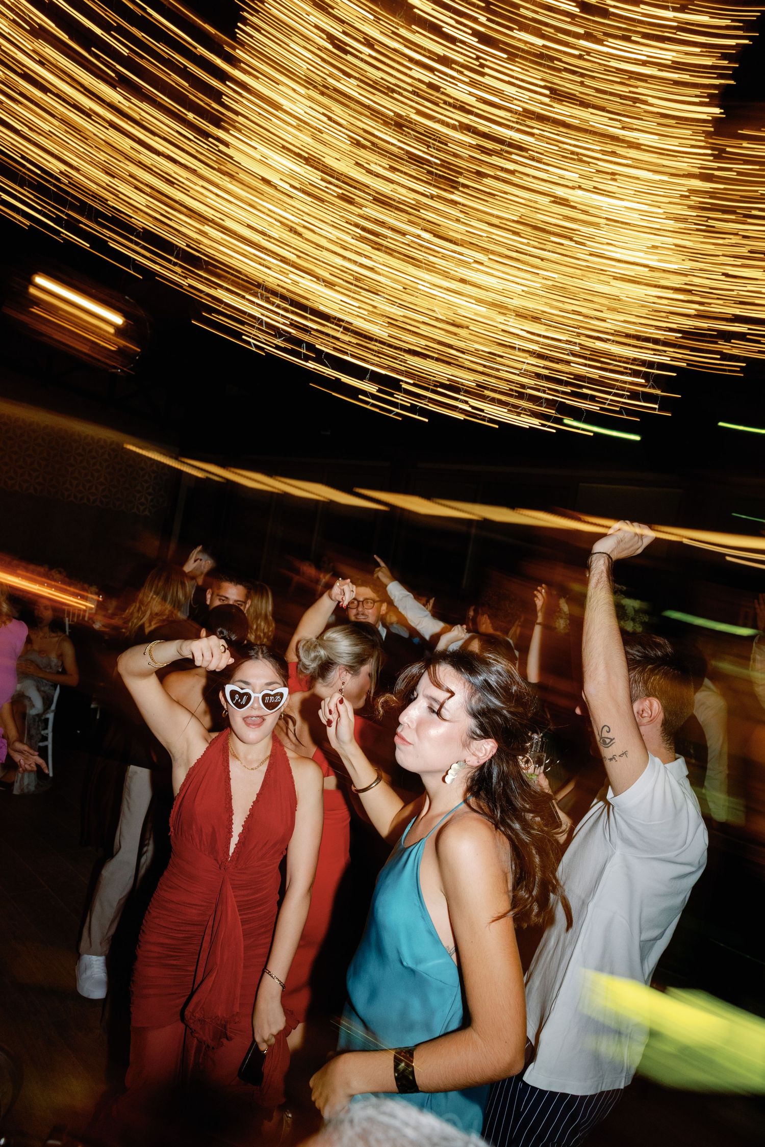 Party guests dancing under dramatic golden ceiling lights.