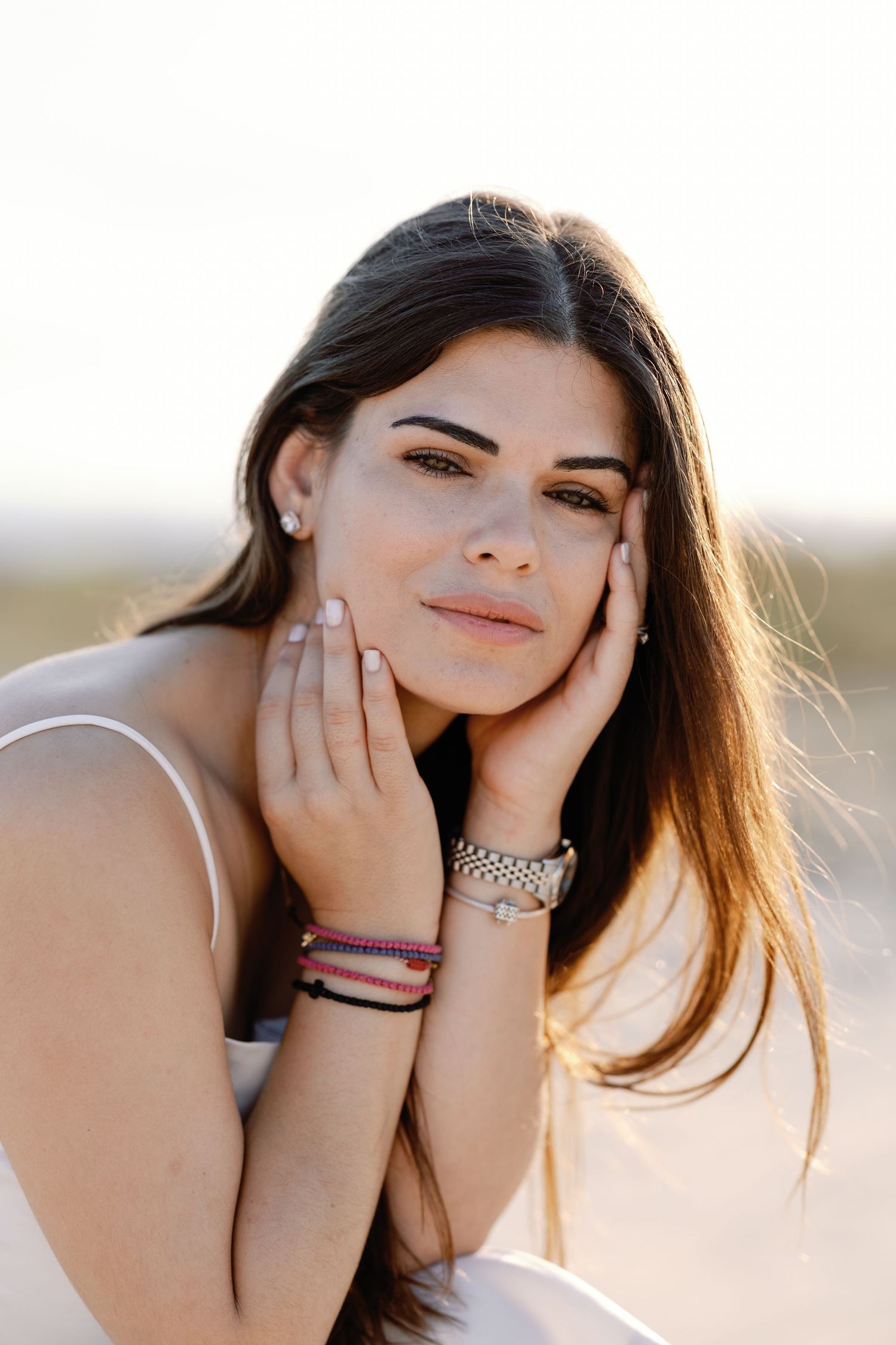 Portrait series of woman in sunlight touching her face with delicate jewelry.
