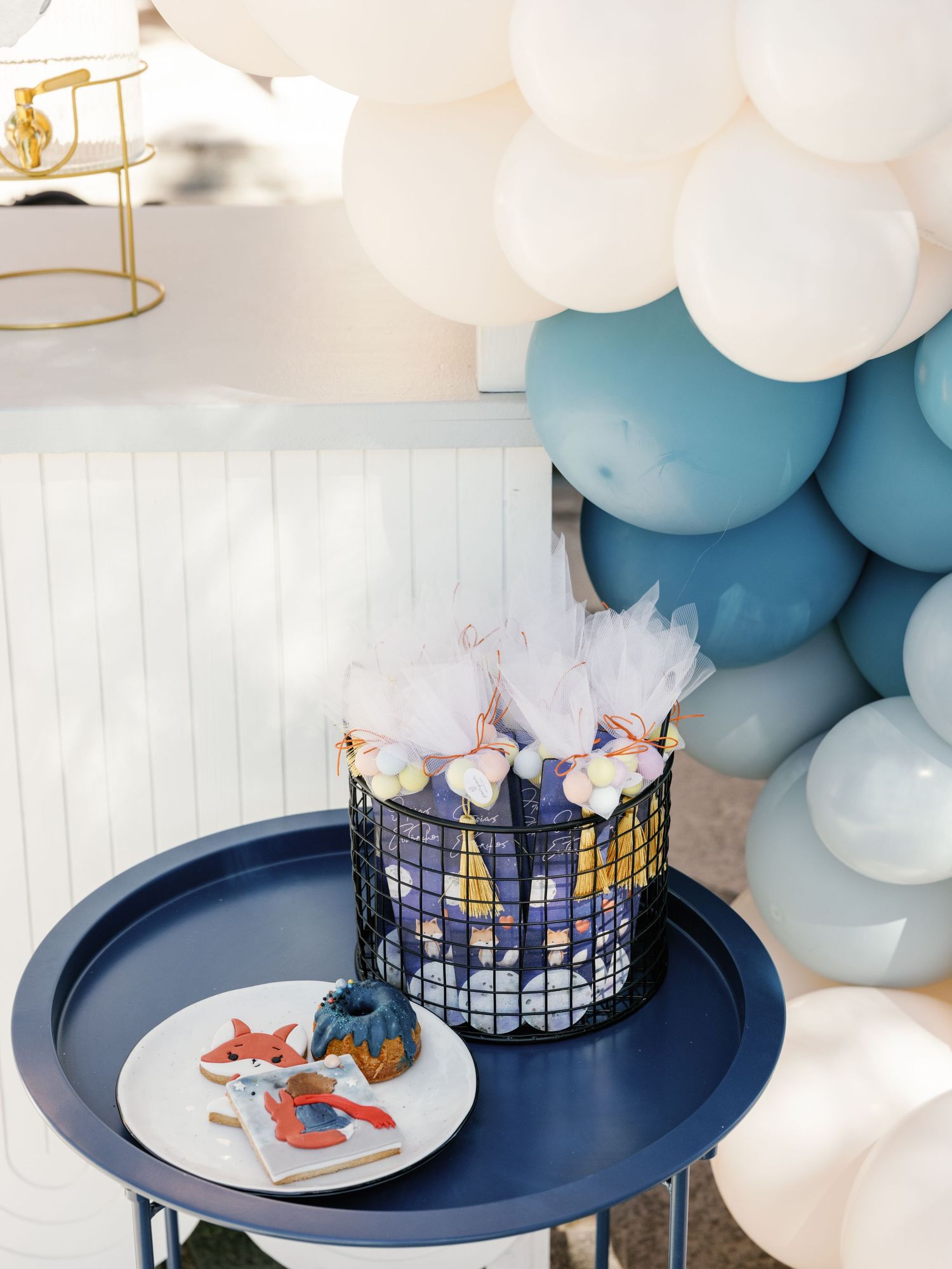 Navy blue cake stand with balloon garland in white and blue tones displays a spider-man themed birthday cake.
