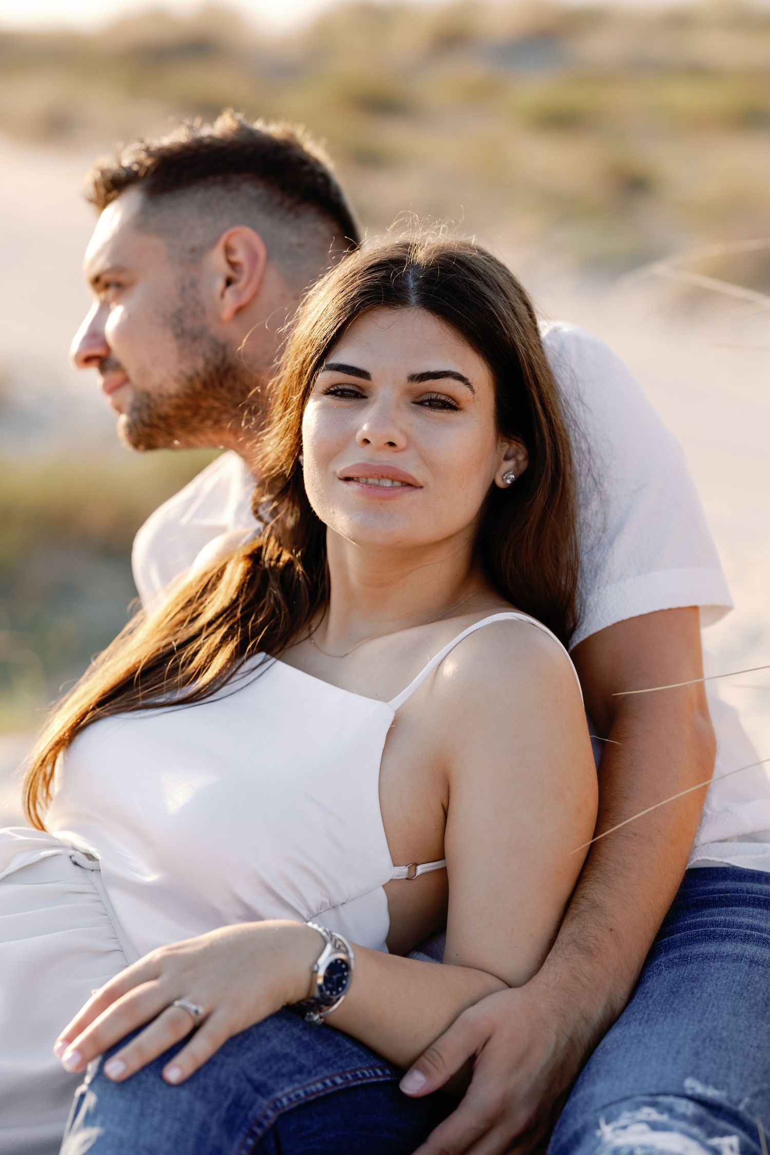 Intimate beach photoshoot with couple in casual white outfits.