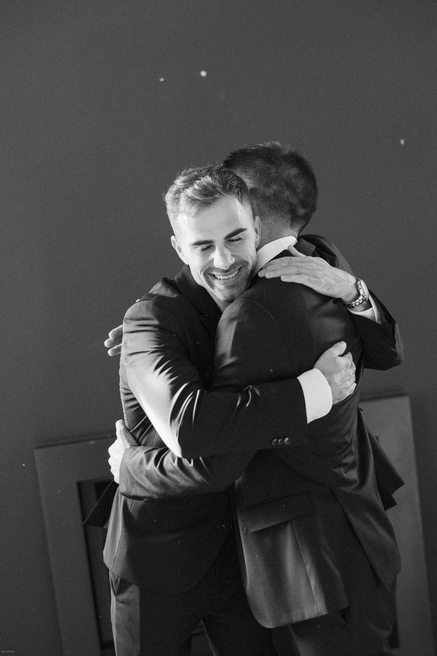 Emotional black and white series showing groomsmen sharing heartfelt embraces.