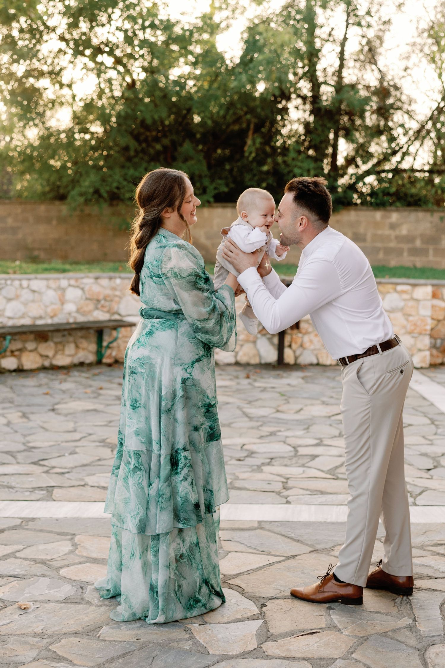 Sweet family interaction on stone patio with flowing mint green dress and casual attire.