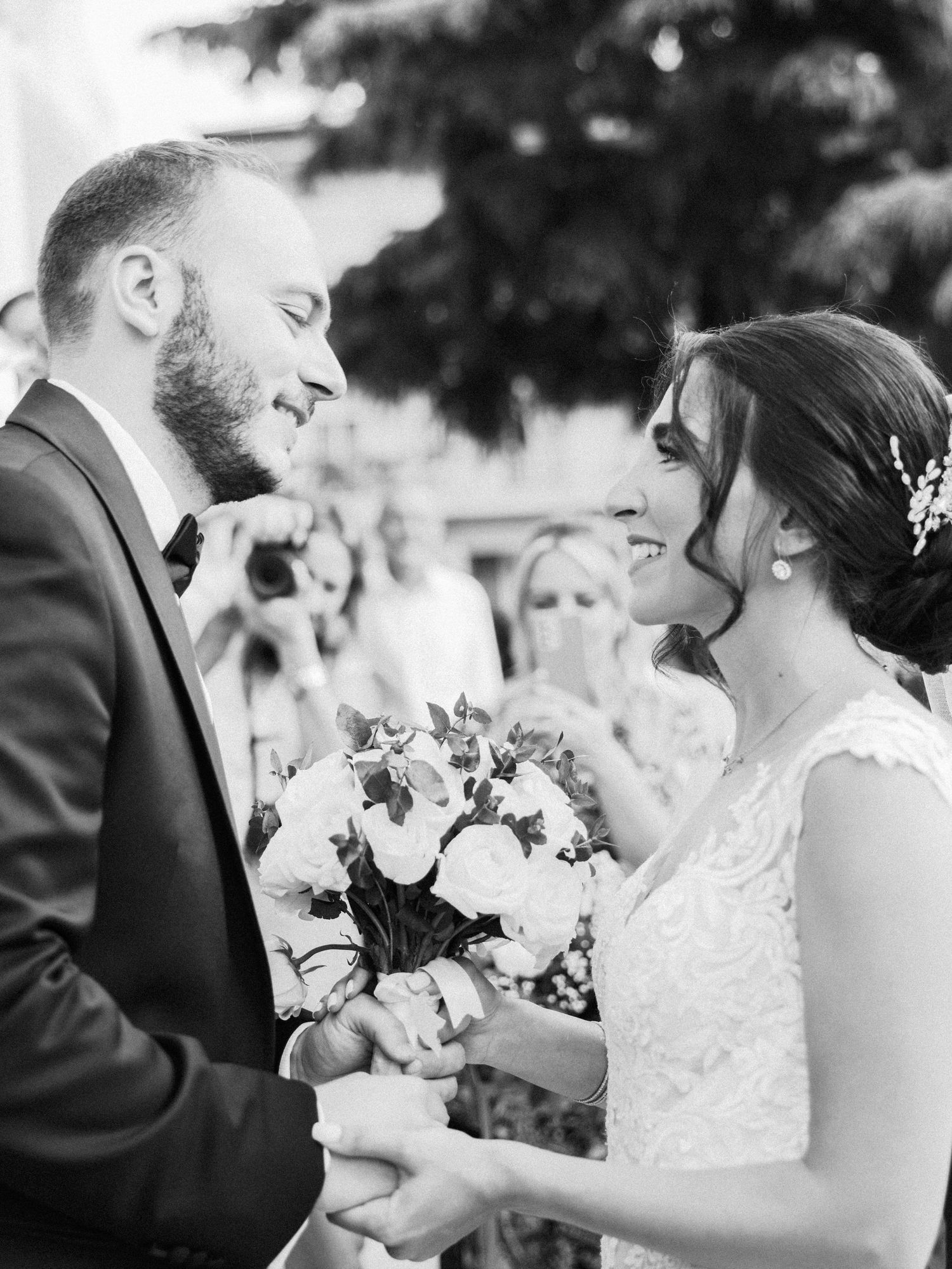 A tender wedding moment captured in black and white as a couple shares an intimate embrace with white floral bouquet.
