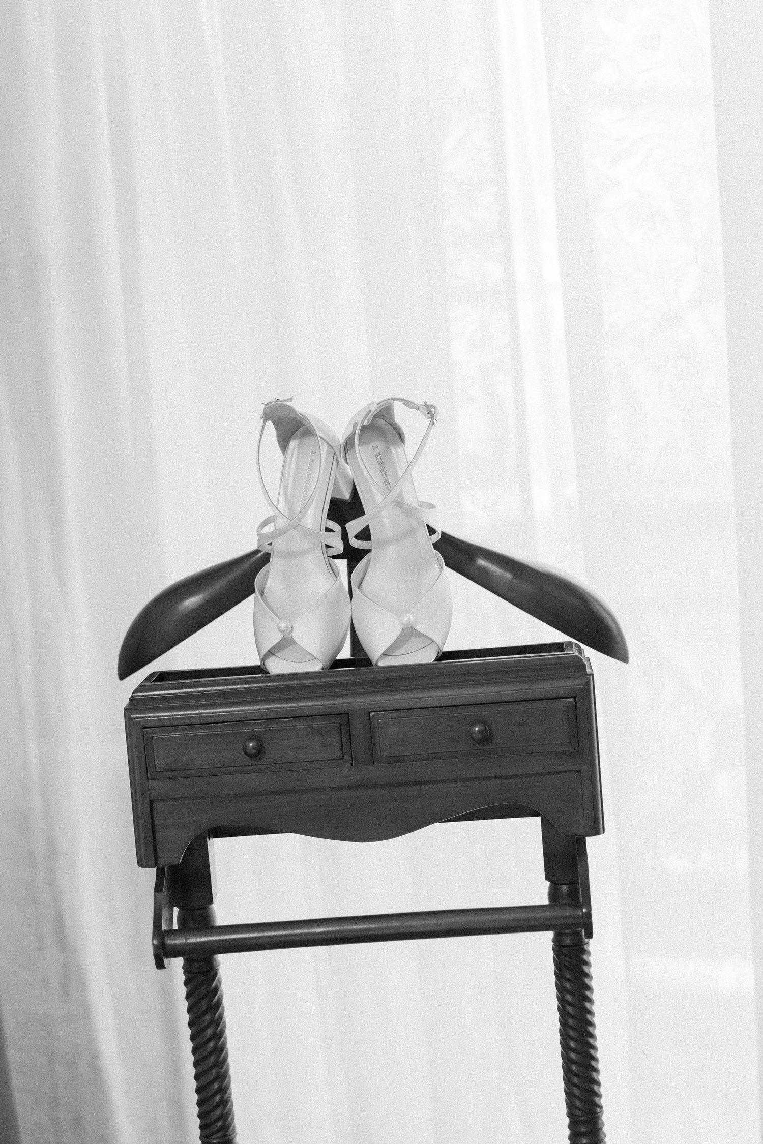 White bridal shoes and black hangers arranged on antique wooden table.