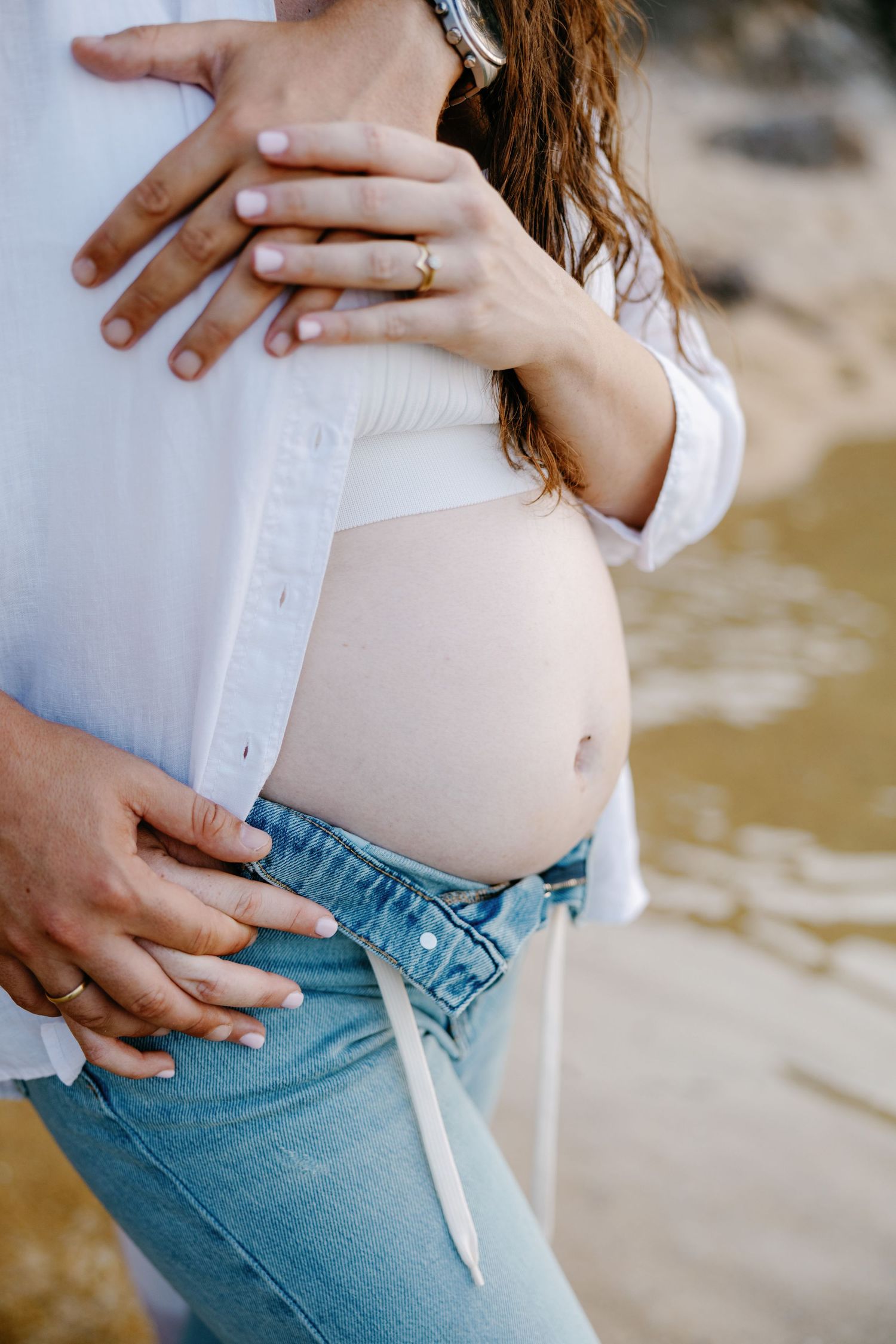 Close-up shots of a couple's hands showing tender moments on a beach.