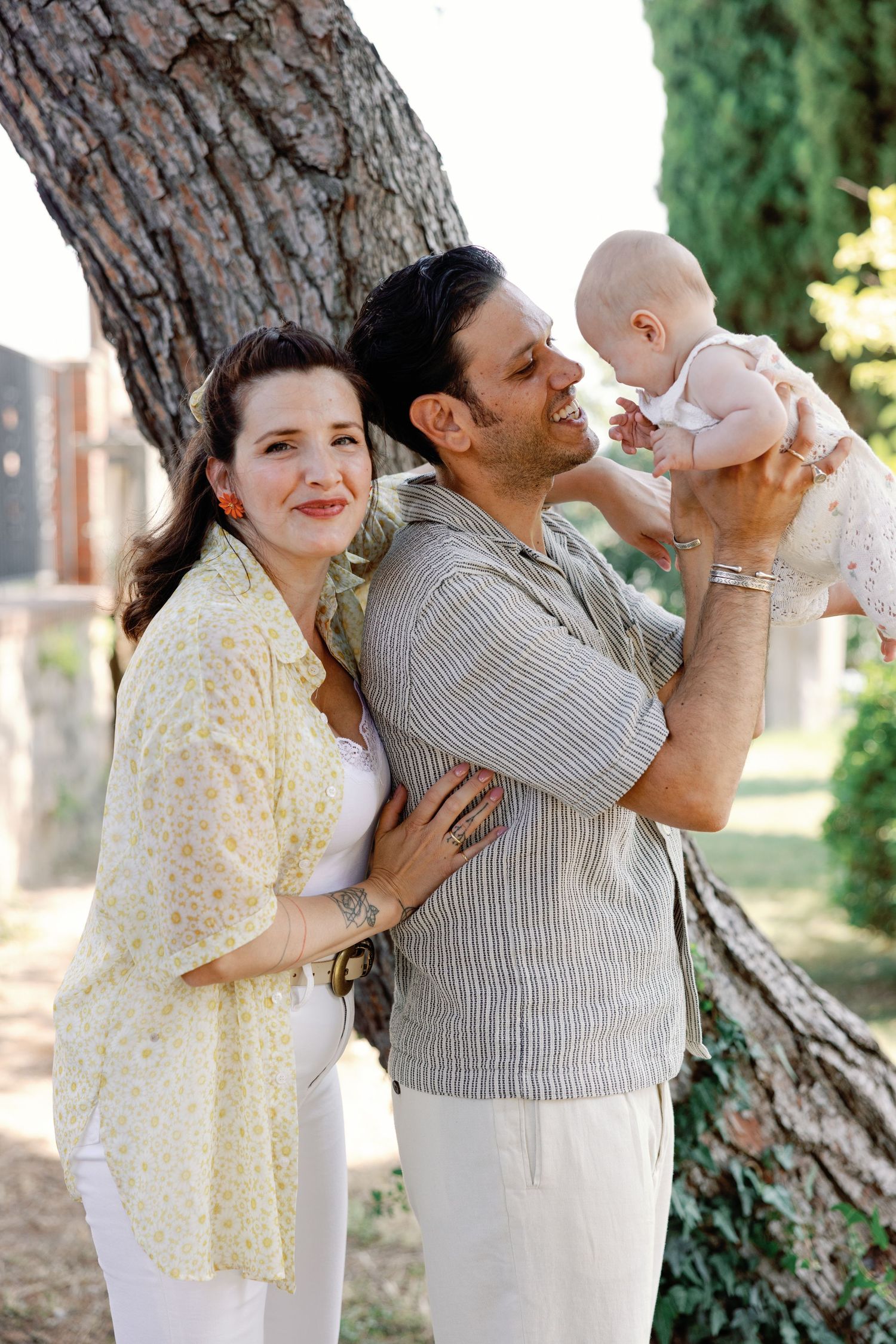 Tender family moment captured under a large tree trunk in a garden setting.