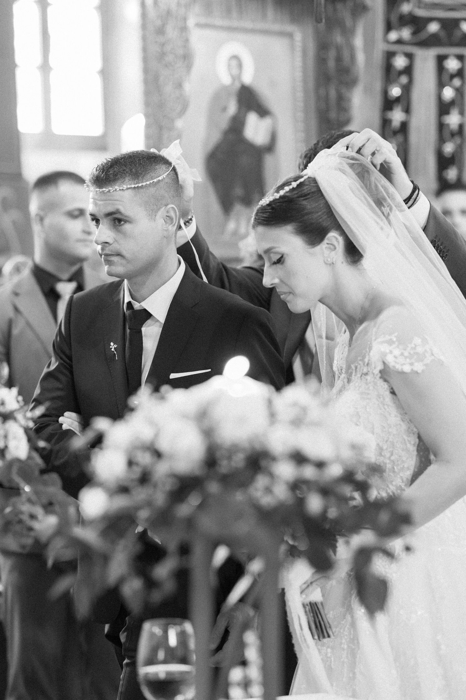 Black and white photo of a traditional church wedding ceremony with floral decorations.