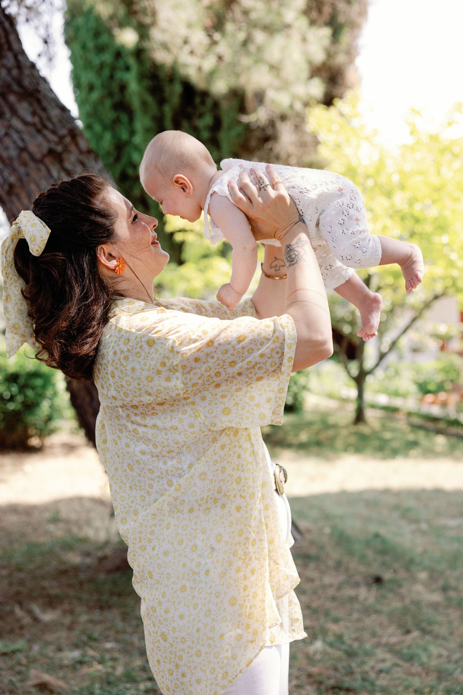 Candid outdoor scene showing joyful interaction in a garden setting with yellow flowers in background.