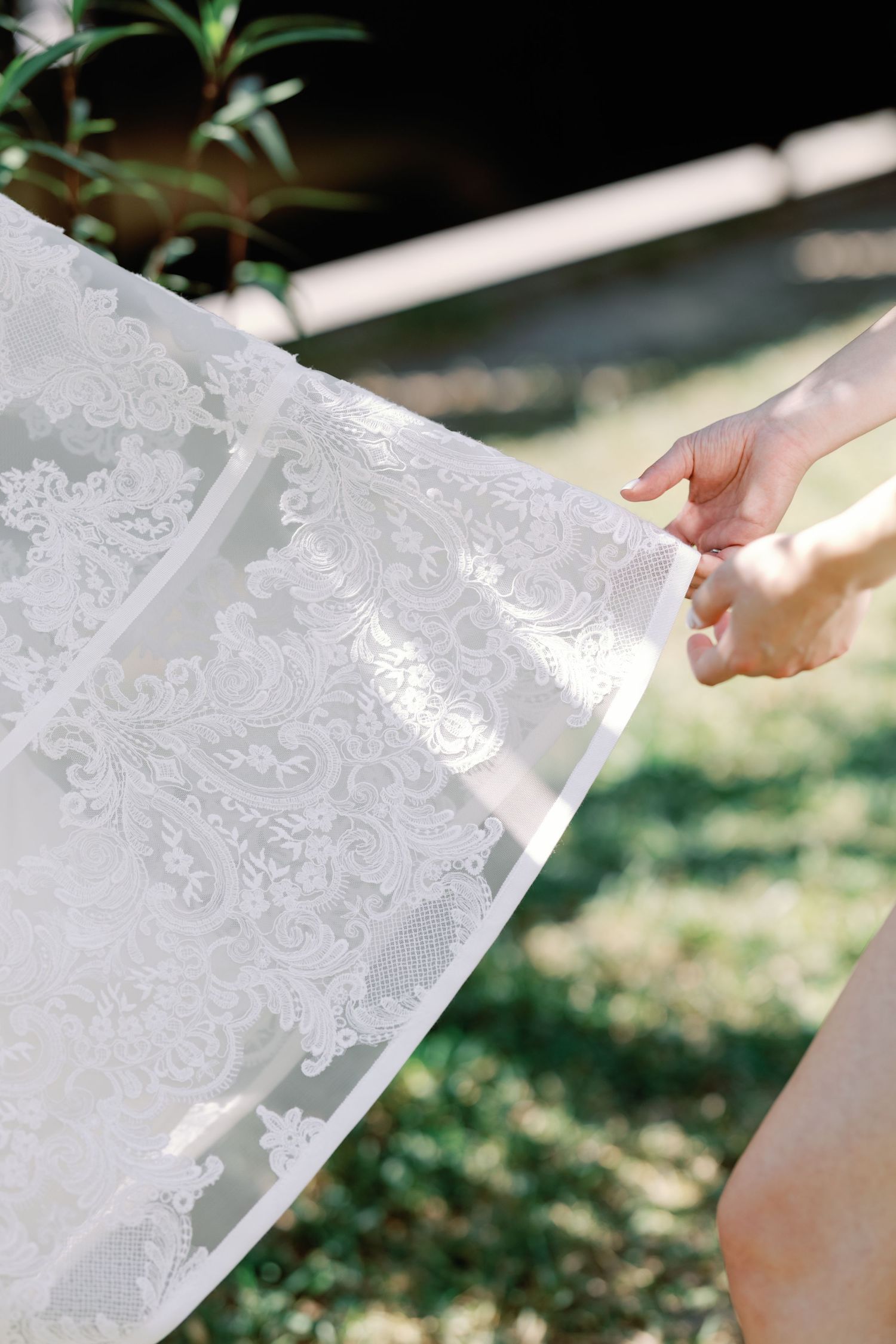 Close-up of hands holding delicate white lace fabric with intricate patterns.