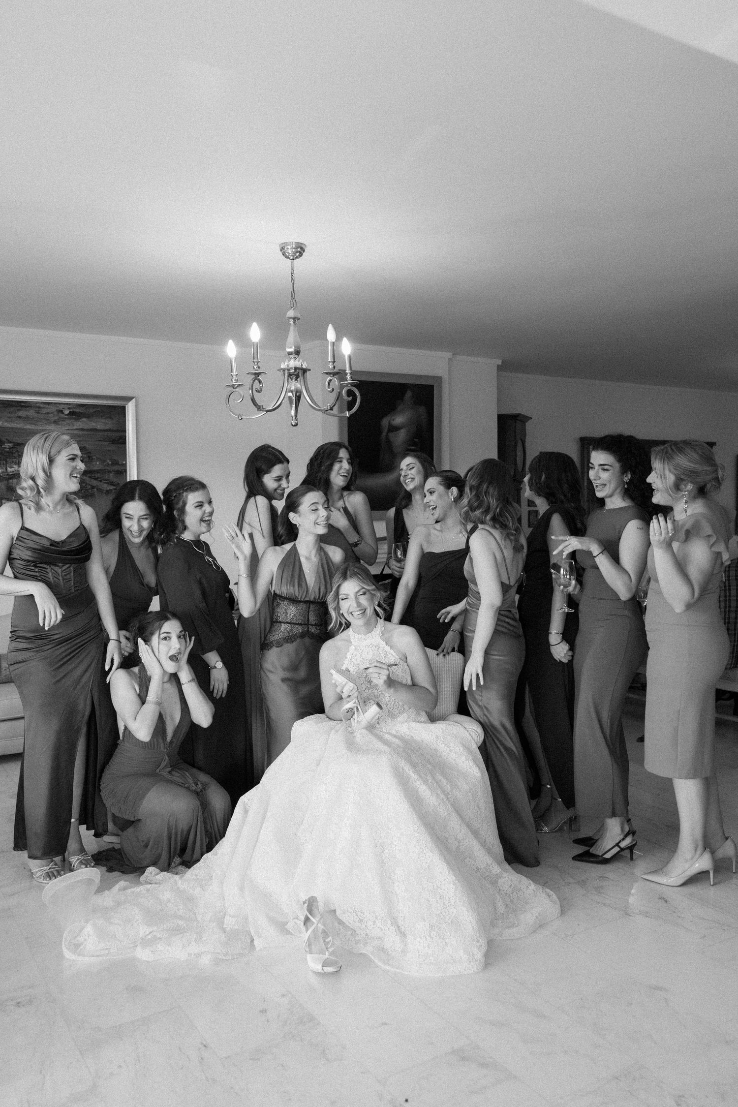 Wedding party members react emotionally during a special reveal moment in a brightly lit room.