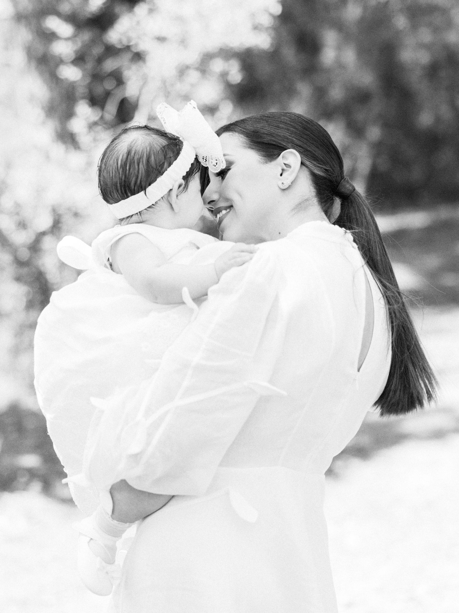 Black and white series of intimate moments showing a couple in white clothing embracing and kissing outdoors.