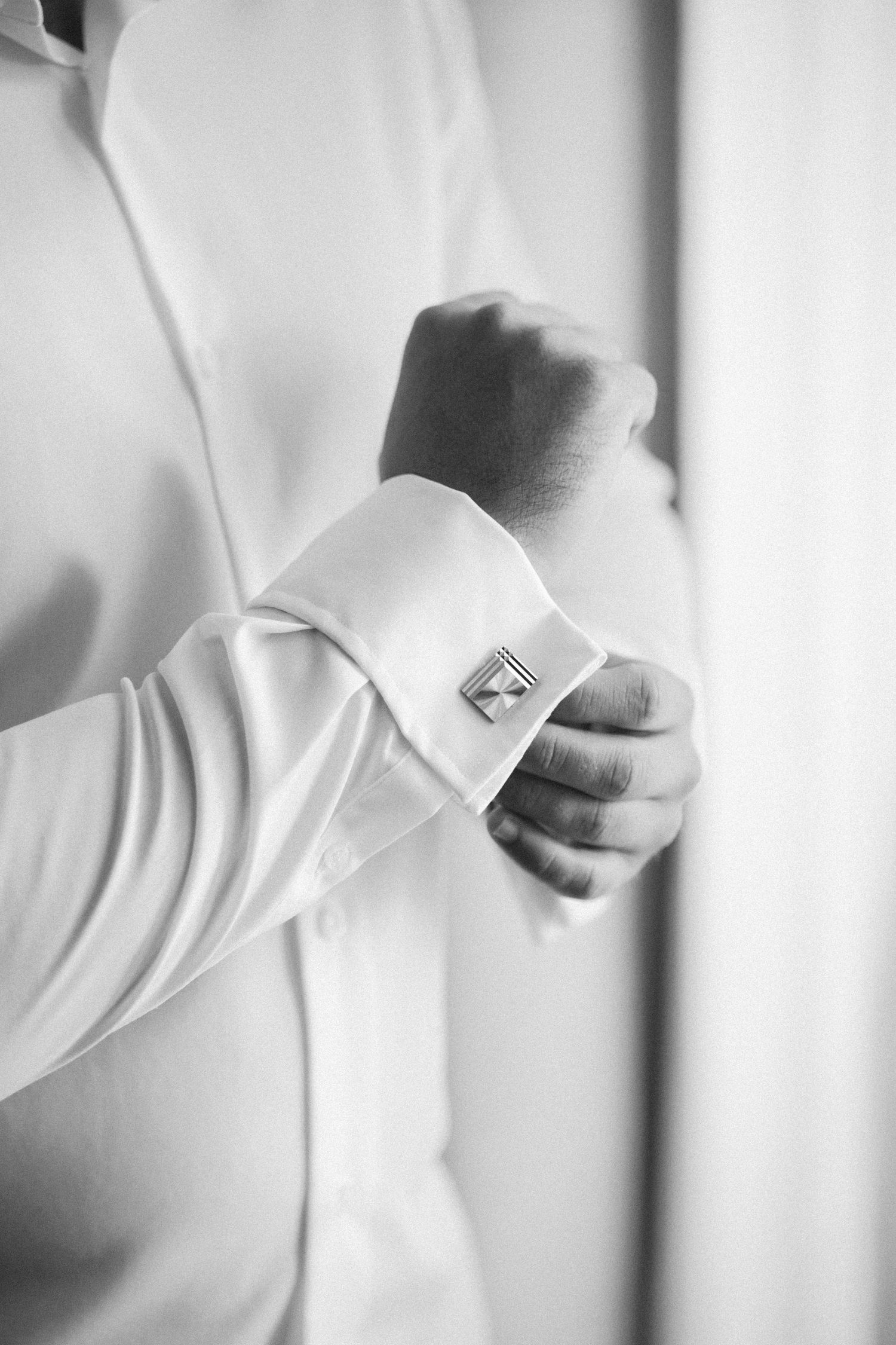 Close-up black and white detail of dress shirt cuffs and cufflinks.