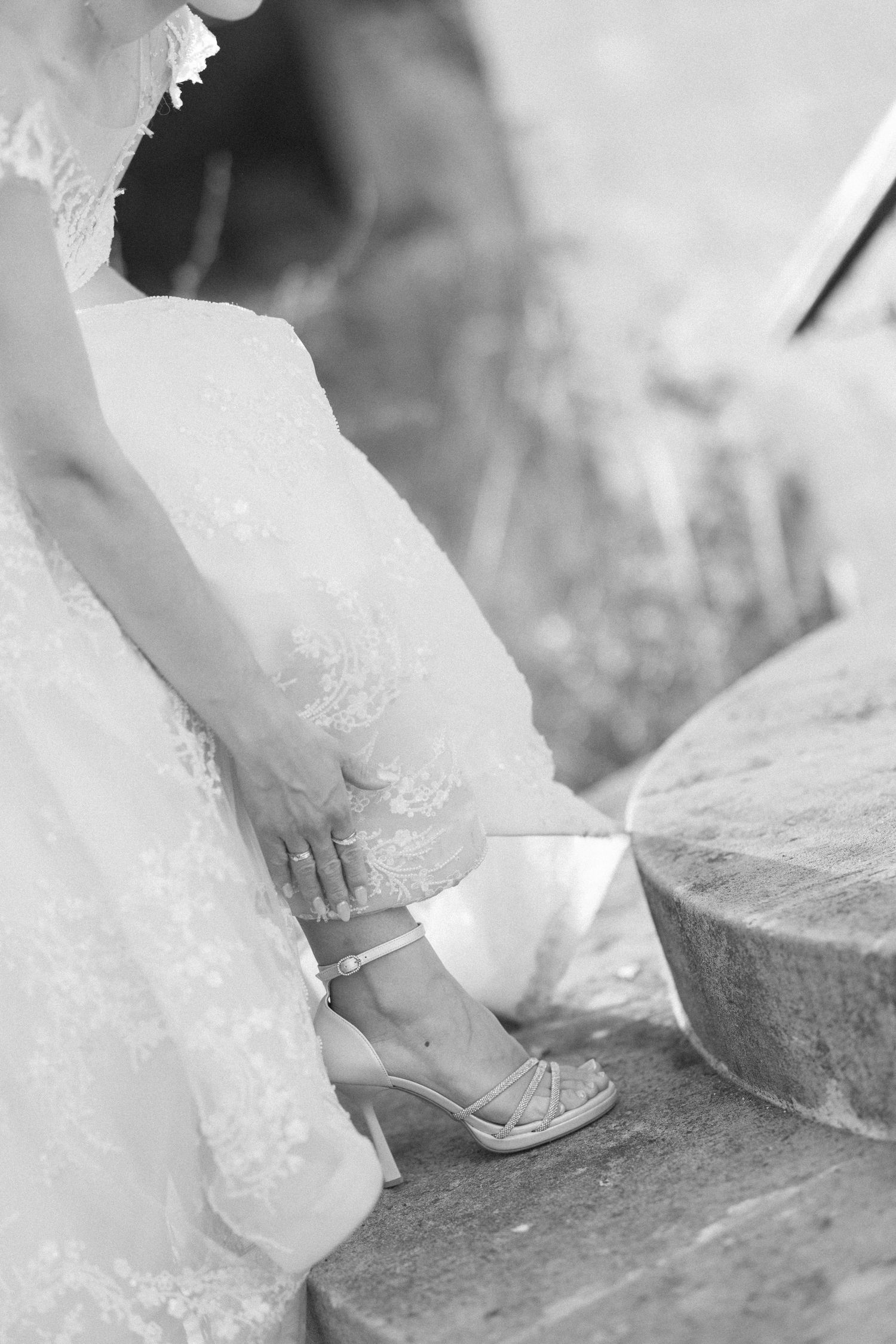 Black and white detail shot of a bride's feet on stone steps.