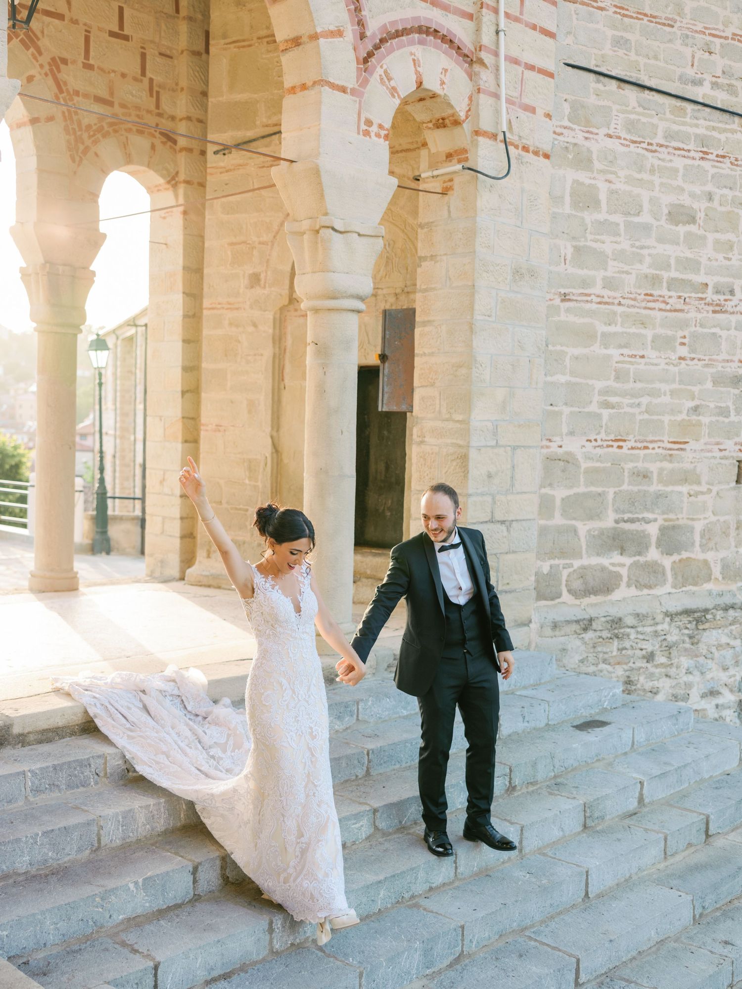 Wedding couple walking through a historic stone colonnade with beautiful architecture.