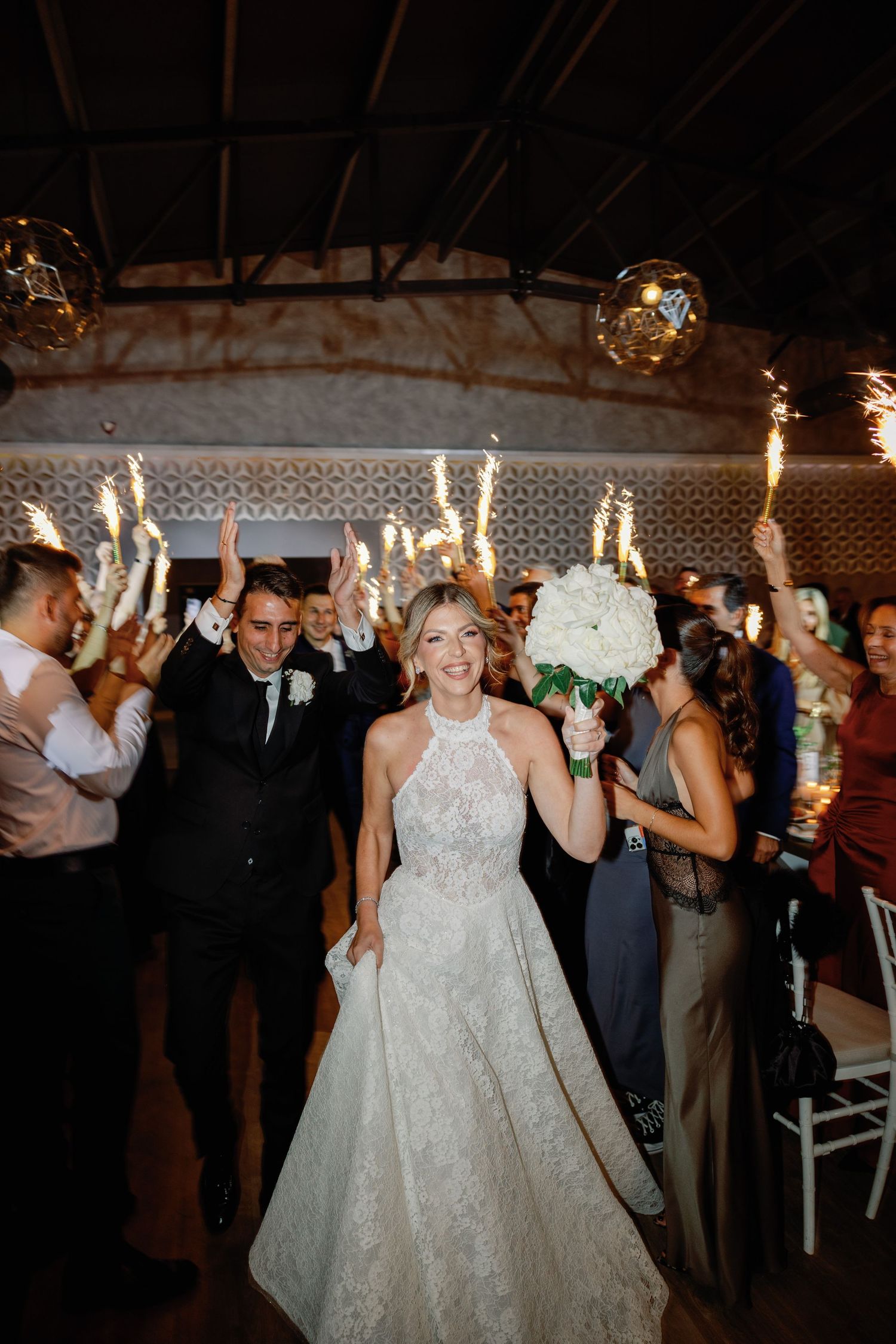 Wedding reception dance floor filled with celebrating guests under hanging lights.