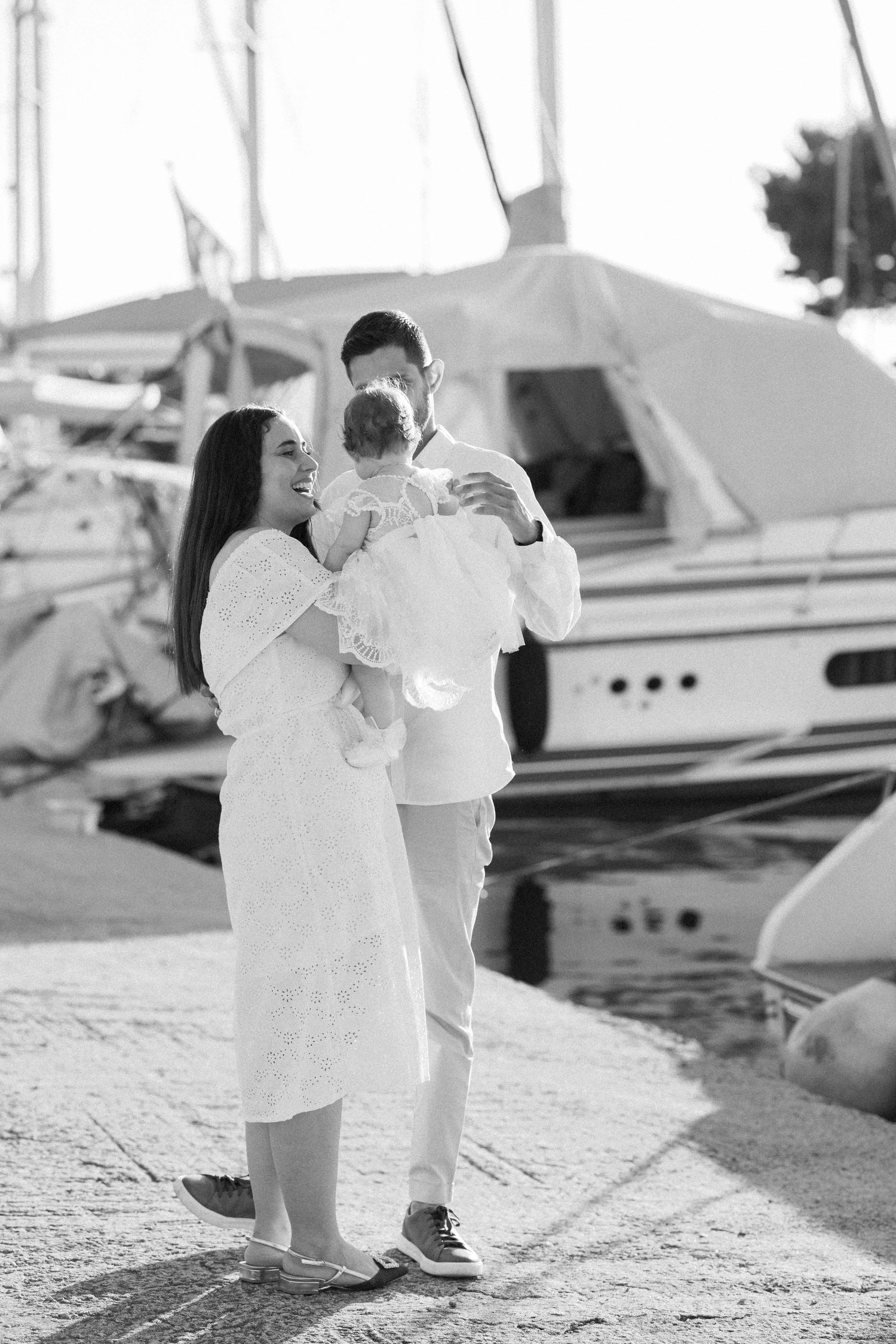 Black and white portraits of a couple dancing by the waterfront with boats in view.