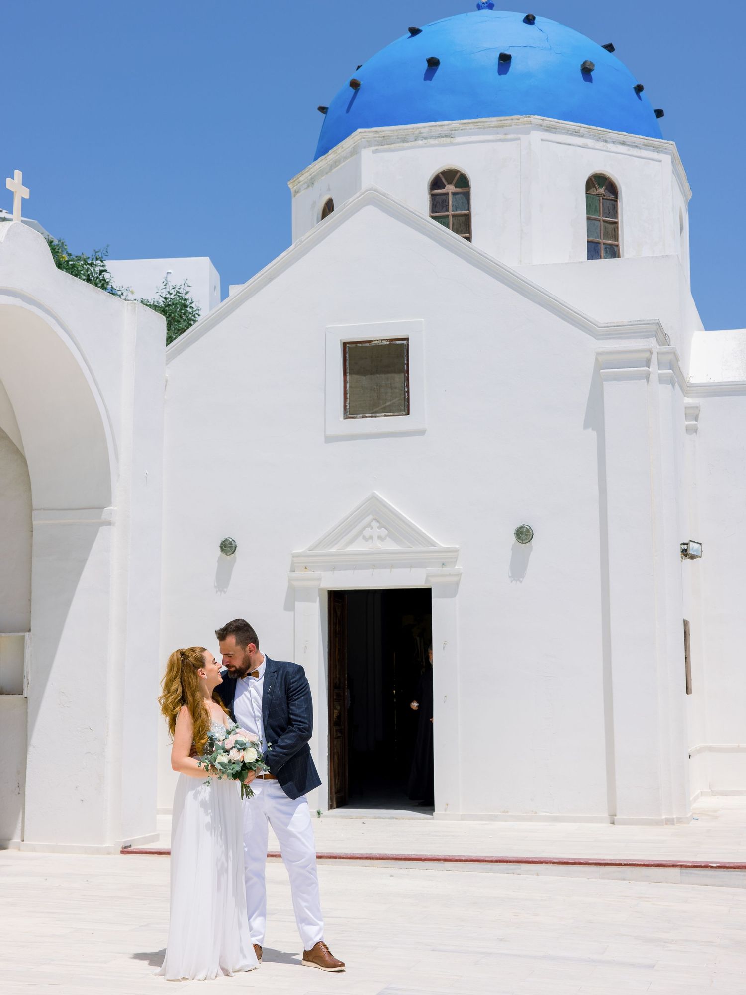 A traditional white Greek Orthodox church with blue domes in Santorini.